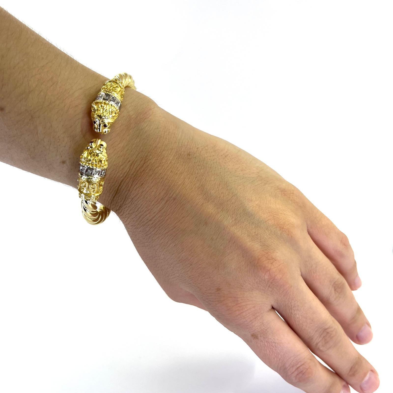 18 Karat Gelbgold 6mm Seilarmreif mit Löwenkopfenden, akzentuiert mit 10 Diamanten im Einzelschliff von Reinheit I1 und Farbe I/J und 4 runden Rubinen. Scharnierdesign mit Weißgold-Akzenten. Das fertige Gewicht beträgt 47 Gramm.