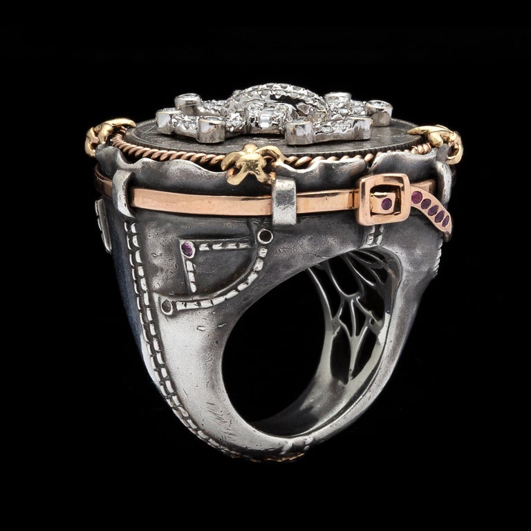 Combining European and American motifs, this unique silver, 18k yellow & rose gold ring is a bold statement for your hand! Designed with a round brilliant and baguette-cut diamond Maltese cross, set atop an old British Isles coin, cornered by
