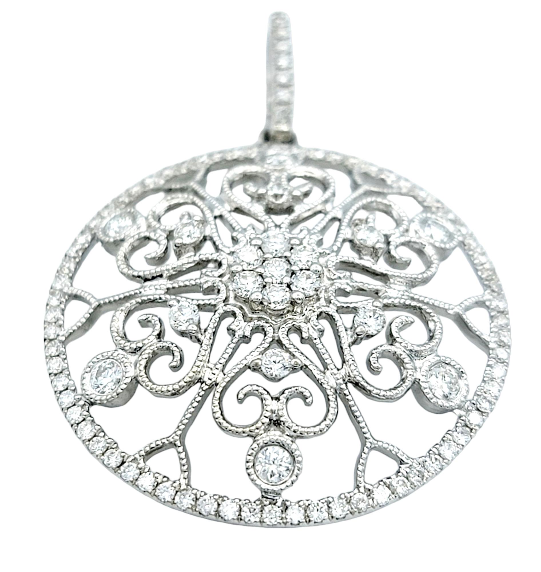 Radiating with timeless charm, this captivating diamond pendant is an embodiment of elegance and sophistication. Set in opulent 14 karat white gold, the pendant takes the form of a resplendent circle adorned with an intricate scroll-like design.