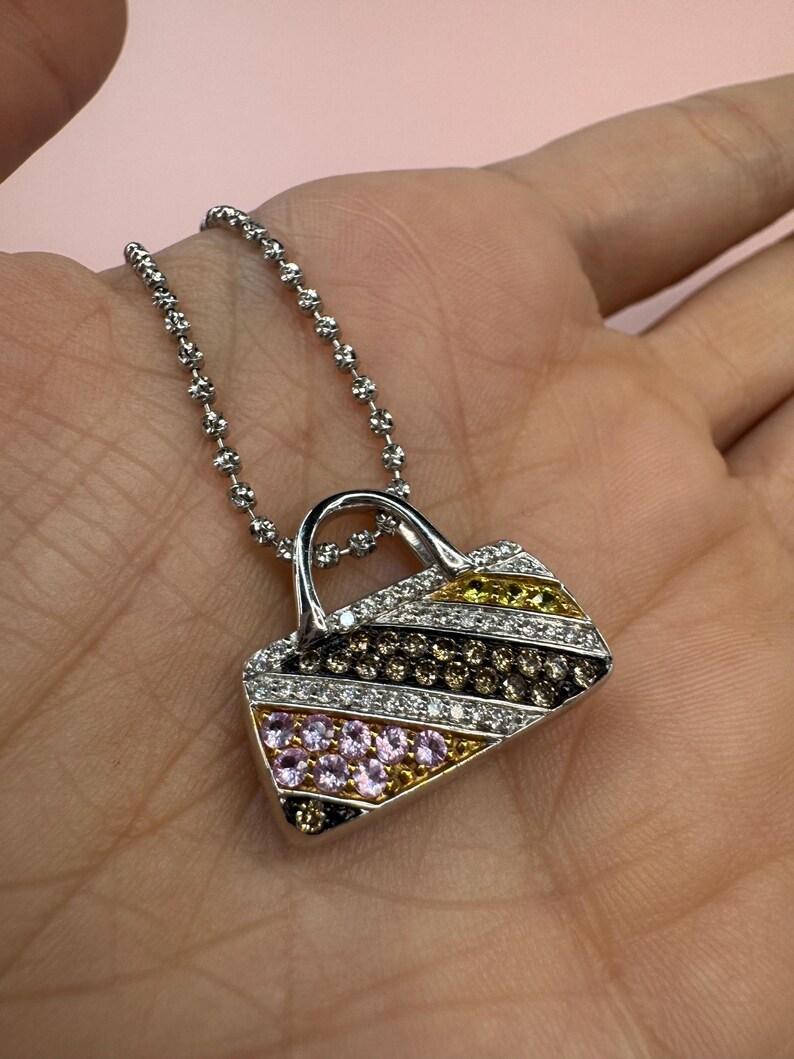 Ciondolo in oro bianco 18 carati con motivo a borsetta con brillanti rotondi e zaffiri multicolore su una catena con perline e diamanti. 
Diamanti - 0,45 Carati
Zaffiri - 0,50 Carati