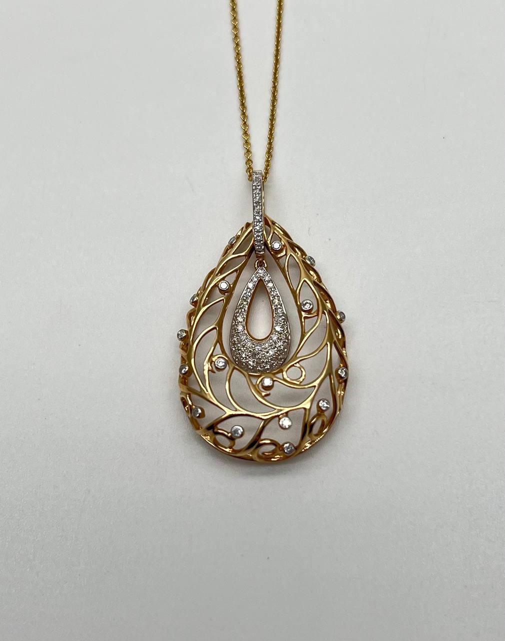Questo pezzo squisito presenta un design a goccia incastonato in oro 14k. Il pendente è impreziosito da una serie di diamanti bianchi, per un totale di 0,36 carati, disposti in modo intricato lungo il design traforato. L'elemento centrale è una