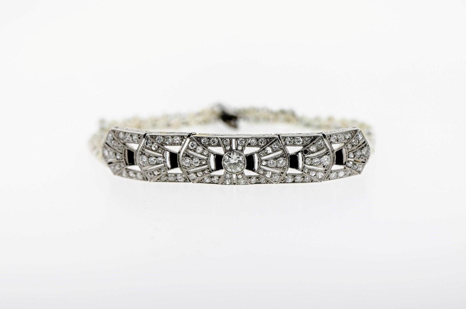 A gorgeous 1920s Art Deco period bracelet.  The articulated platinum plaque centers a 0.70 carat old round diamond, and six calibre cut black Onyx and old cut Diamonds radiate outward, each end with three strands of Natural Seed Pearls. The Pearls