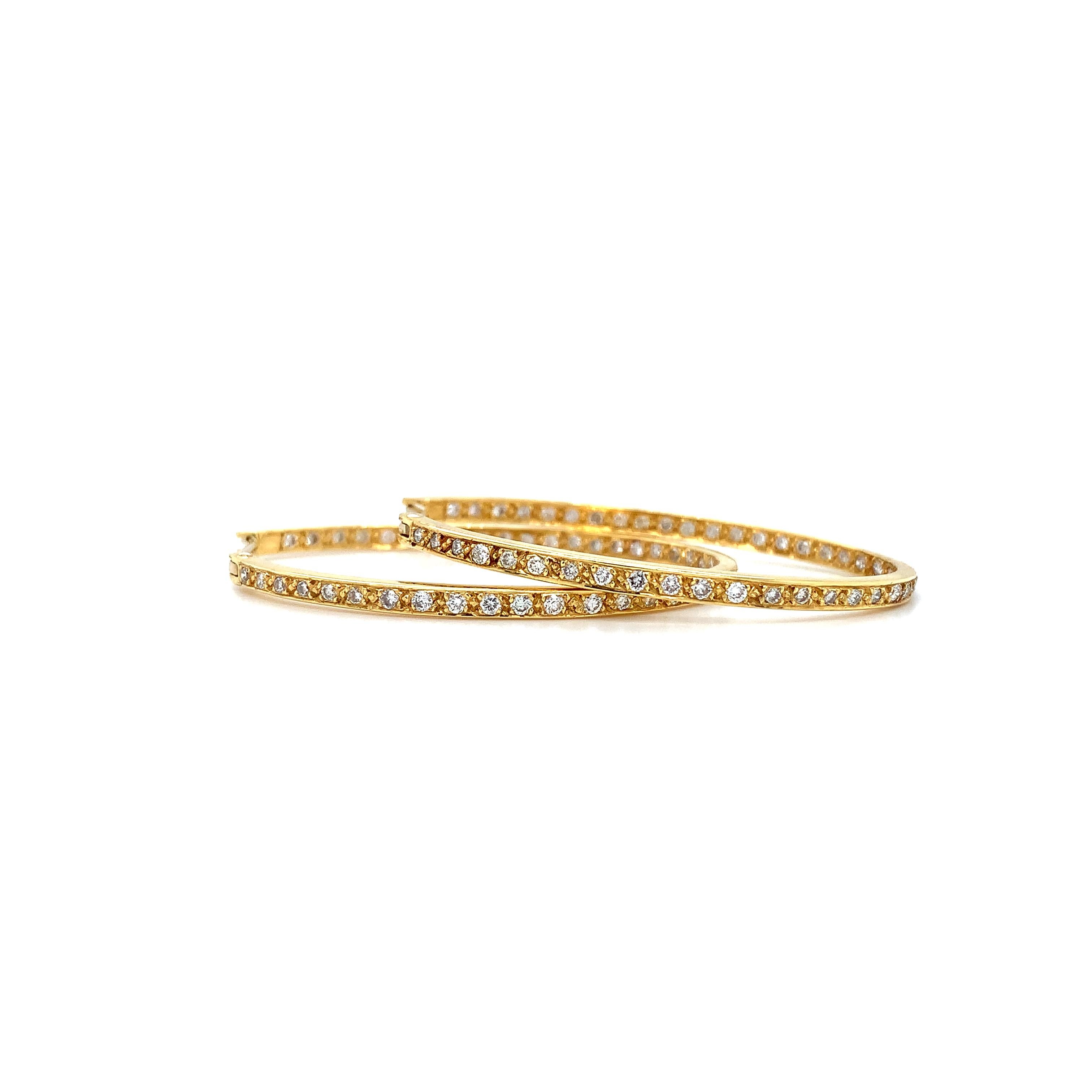 Eleva la tua collezione di gioielli con questi splendidi orecchini a cerchio ovali in oro giallo 18ct. Il design è caratterizzato da cerchi medi con un elegante stile ispirato al tennis, perfetto per aggiungere un tocco di glamour a tema artistico a