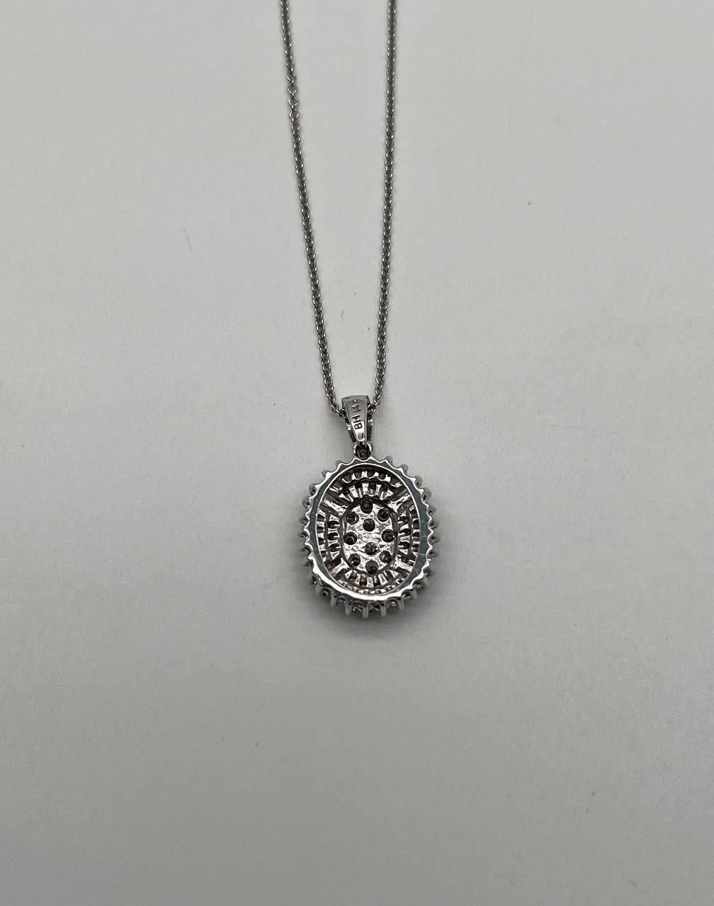 Questa elegante collana con ciondolo, realizzata artigianalmente, presenta un design ovale abbagliante. Il centro è ornato da un grappolo di diamanti scintillanti, circondato da un'aureola di pietre a taglio baguette e rotondo, che creano uno