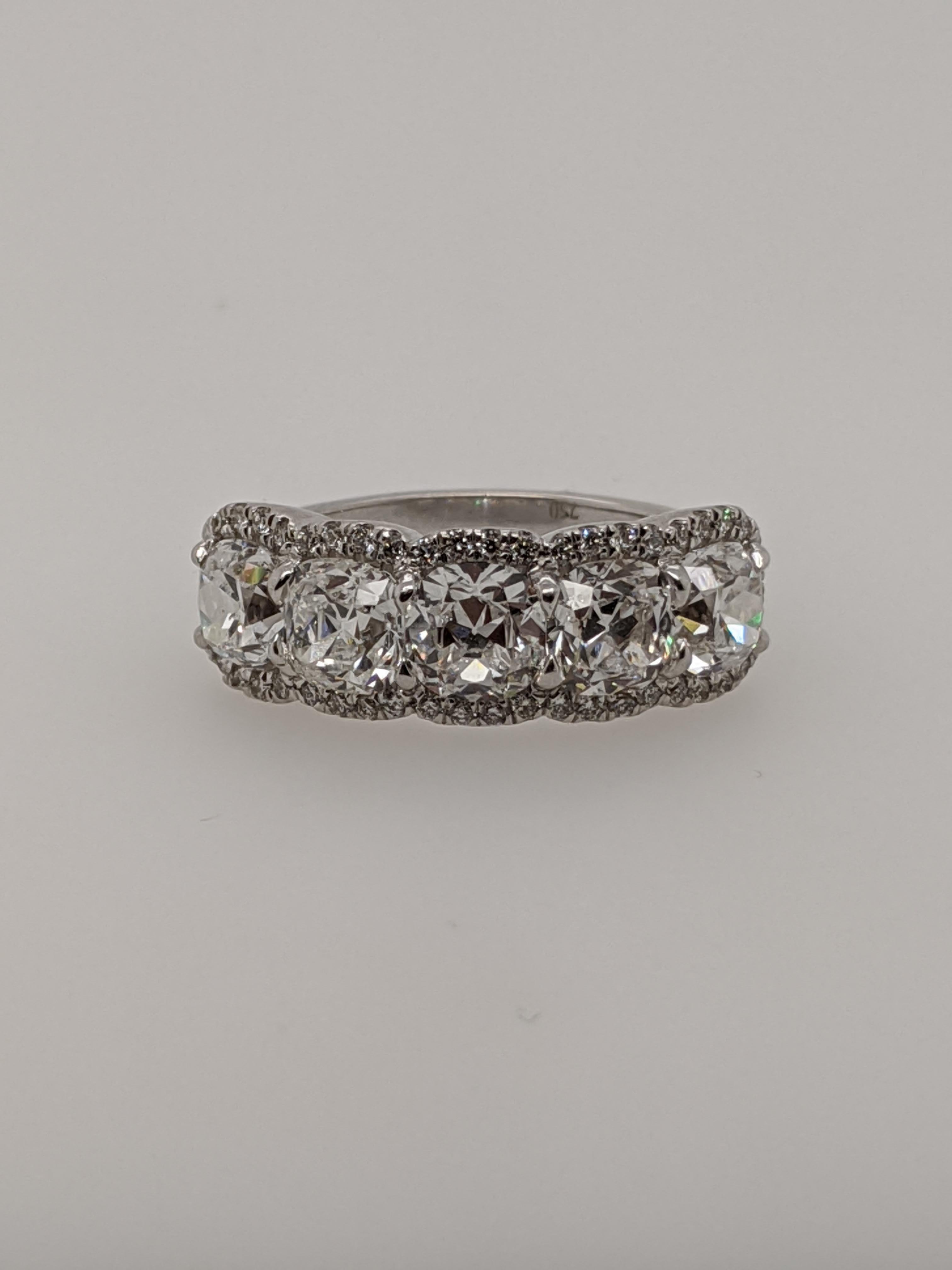 Exquisite diamond ring spanning the top of the finger featuring five cushion cut diamonds (3.31 carat total)  in 18 karat white gold with 46 smaller diamonds as accents on the outside.   We call this ring 