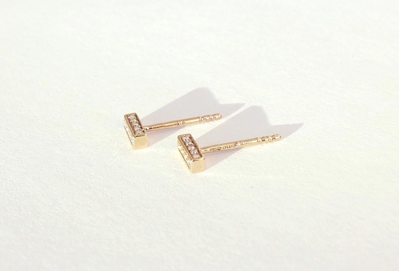 These bar-shaped stud earrings are encrusted with brilliant white diamonds pave-set on three sides.  Measuring approximately 7 mm across, they feature fifteen white diamonds for a total of 0.11 carats, set in 9-karat yellow gold with a post and