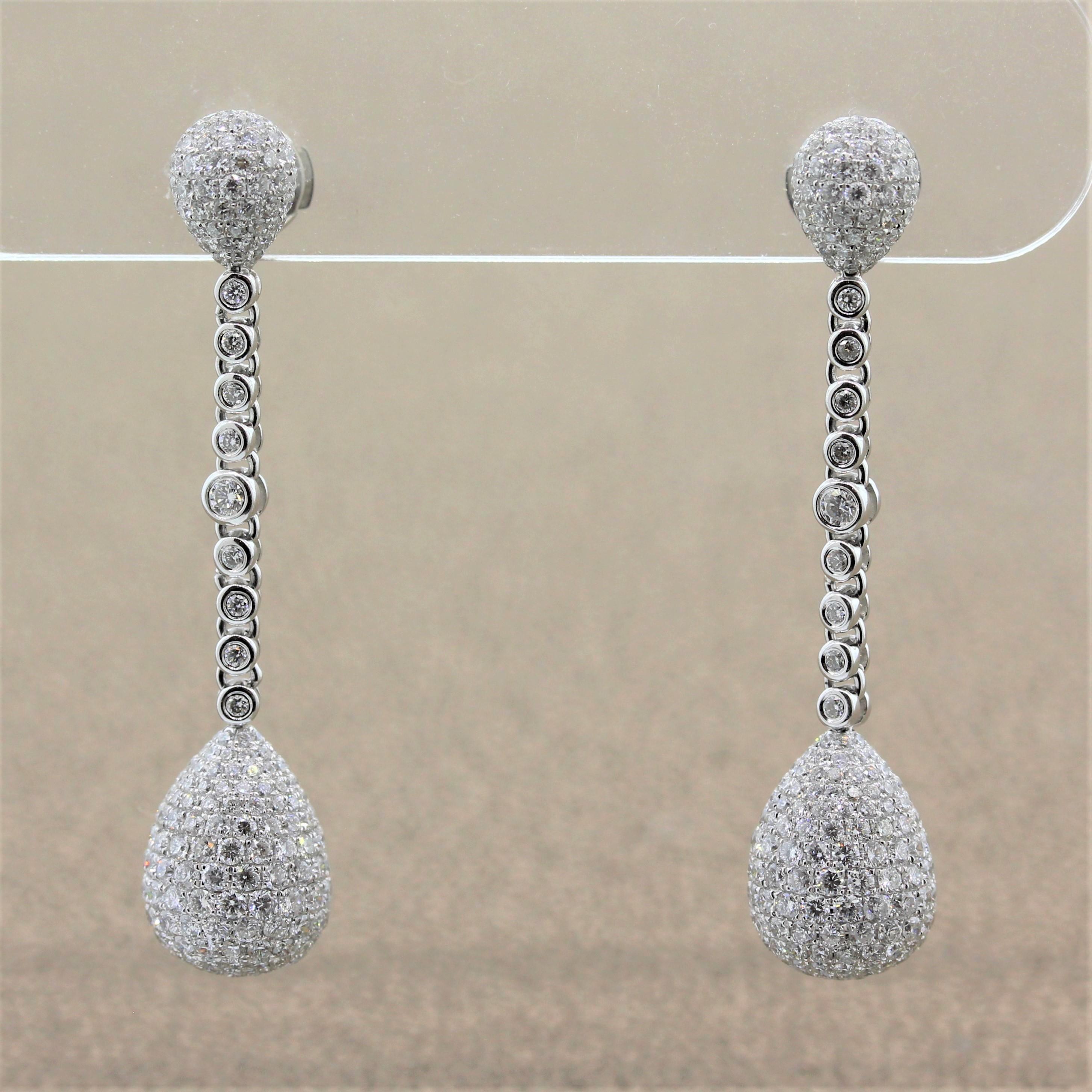 An elegant pair of drop earrings featuring 4.40 carats of round brilliant cut diamonds pave set in an 18K white gold setting. The two pear shaped drops are attached by a string of diamonds adding sparkle from top to bottom.

Earring Length: 1.65