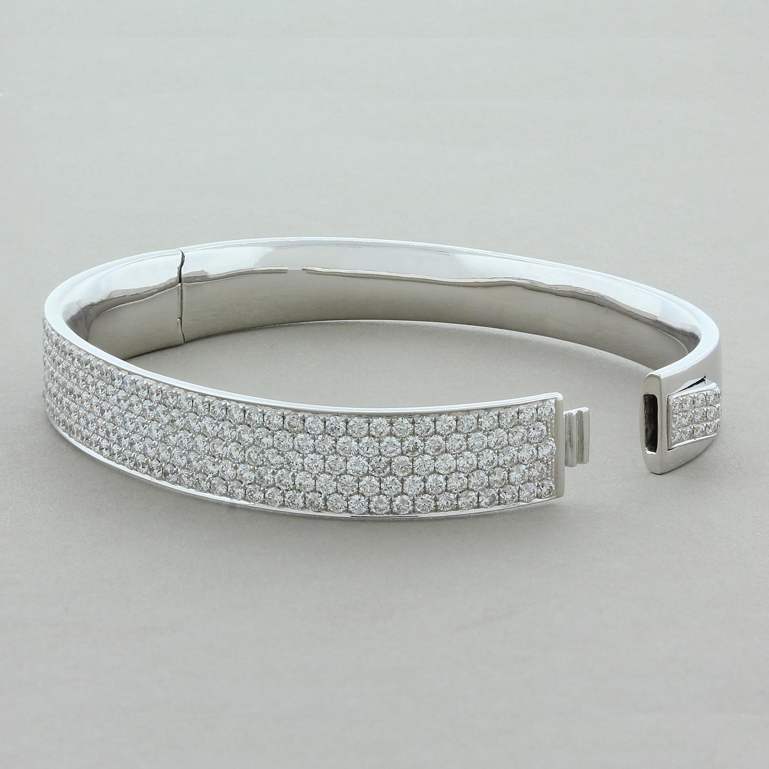 This elegant hard bracelet features 5.69 carats of sparkling round brilliant cut diamonds that are delicately pave set in 18K white gold. The diamonds blanket the front half of this oval shaped bracelet. The lock carries the same pave set diamonds