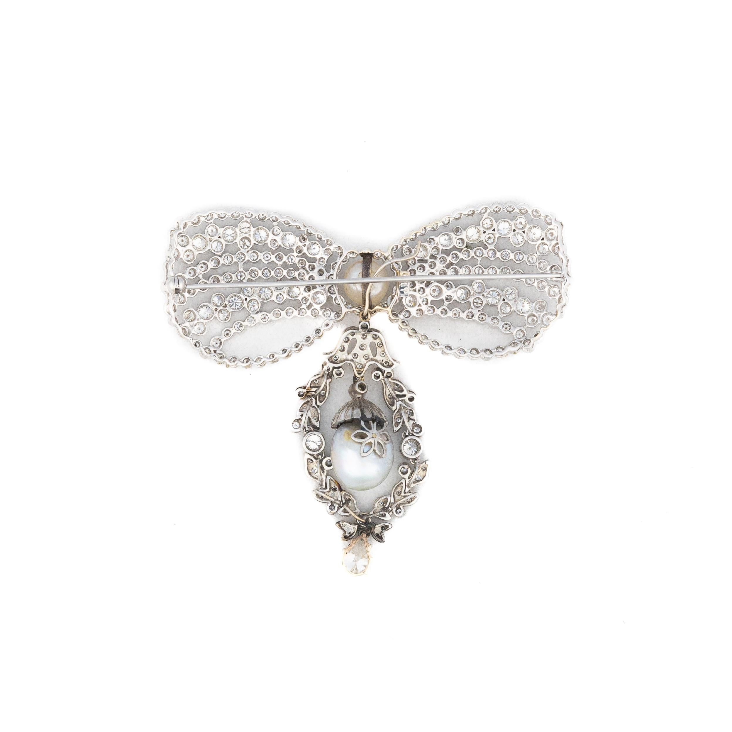 Schleifenbrosche mit Diamanten und Perlen

Diese bezaubernde Brosche ist ein Meisterwerk der Eleganz. Zwei schimmernde Perlen sind anmutig in strahlendes Weißgold gefasst. Das Design wird von einem atemberaubenden birnenförmigen Diamanten mit einem
