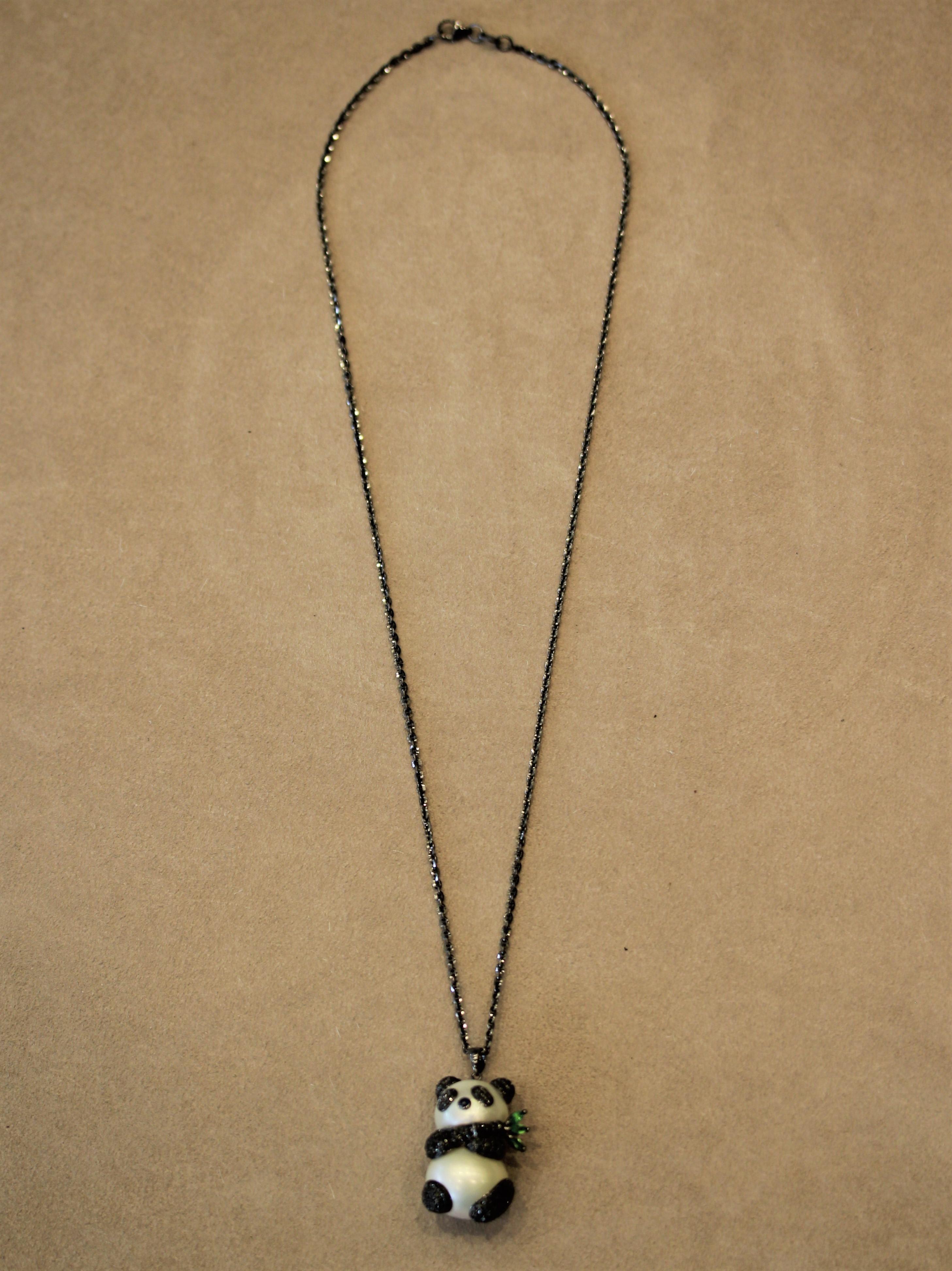 An adorable panda made of 2 South Sea pearls. It is further accented by 1.65 carats of black diamonds which are set in 18k gold with a black rhodium plating. Adding color to the piece are 3 marquise shaped tsavorites filling in as bamboo leaves. The