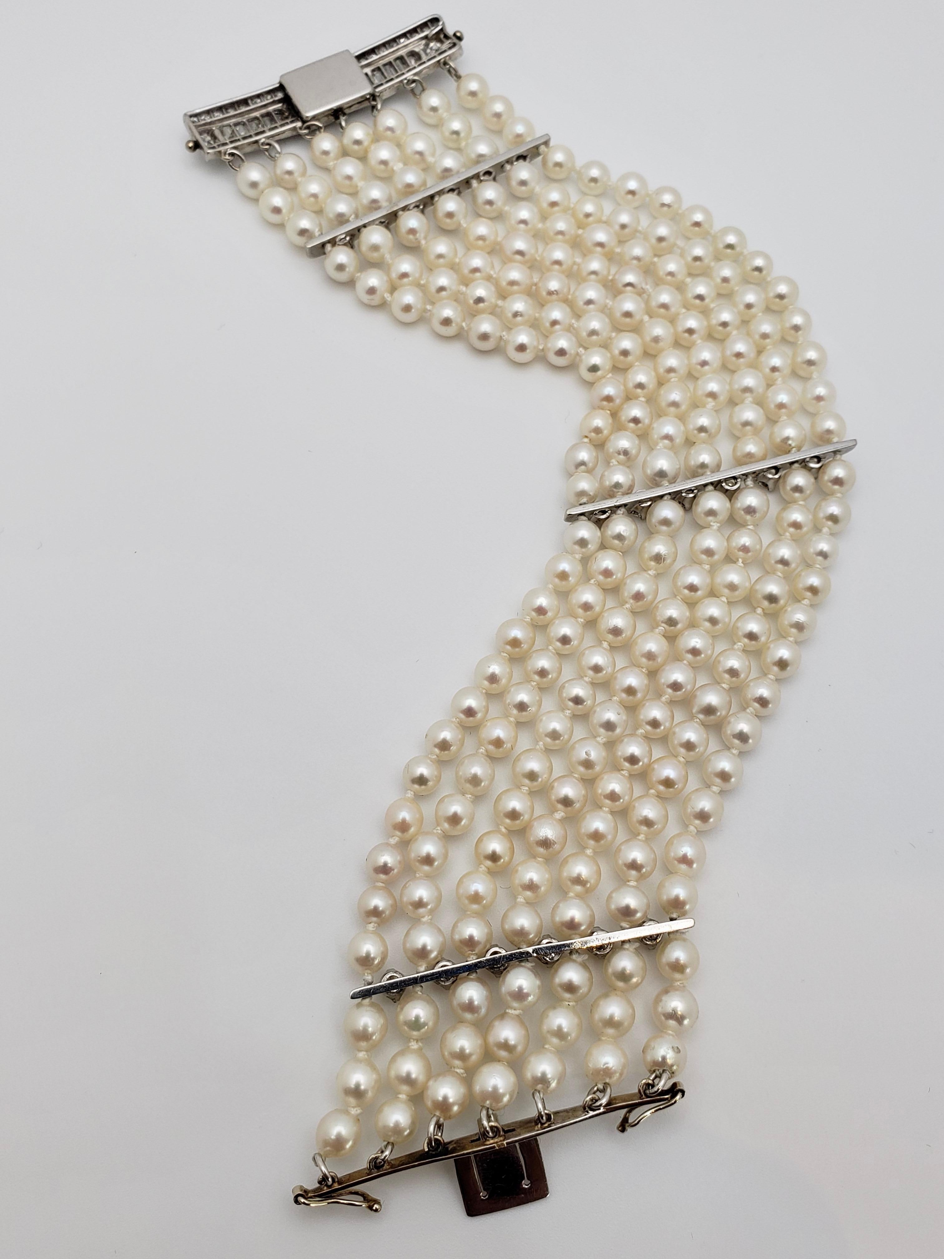 An original diamond platinum and pearl bracelet. This piece features seven rows of round cultured natural pearls each measuring approximately 4.50 mm in diameter. The platinum clasp and dividers are mounted with a total of 76 round single-cut