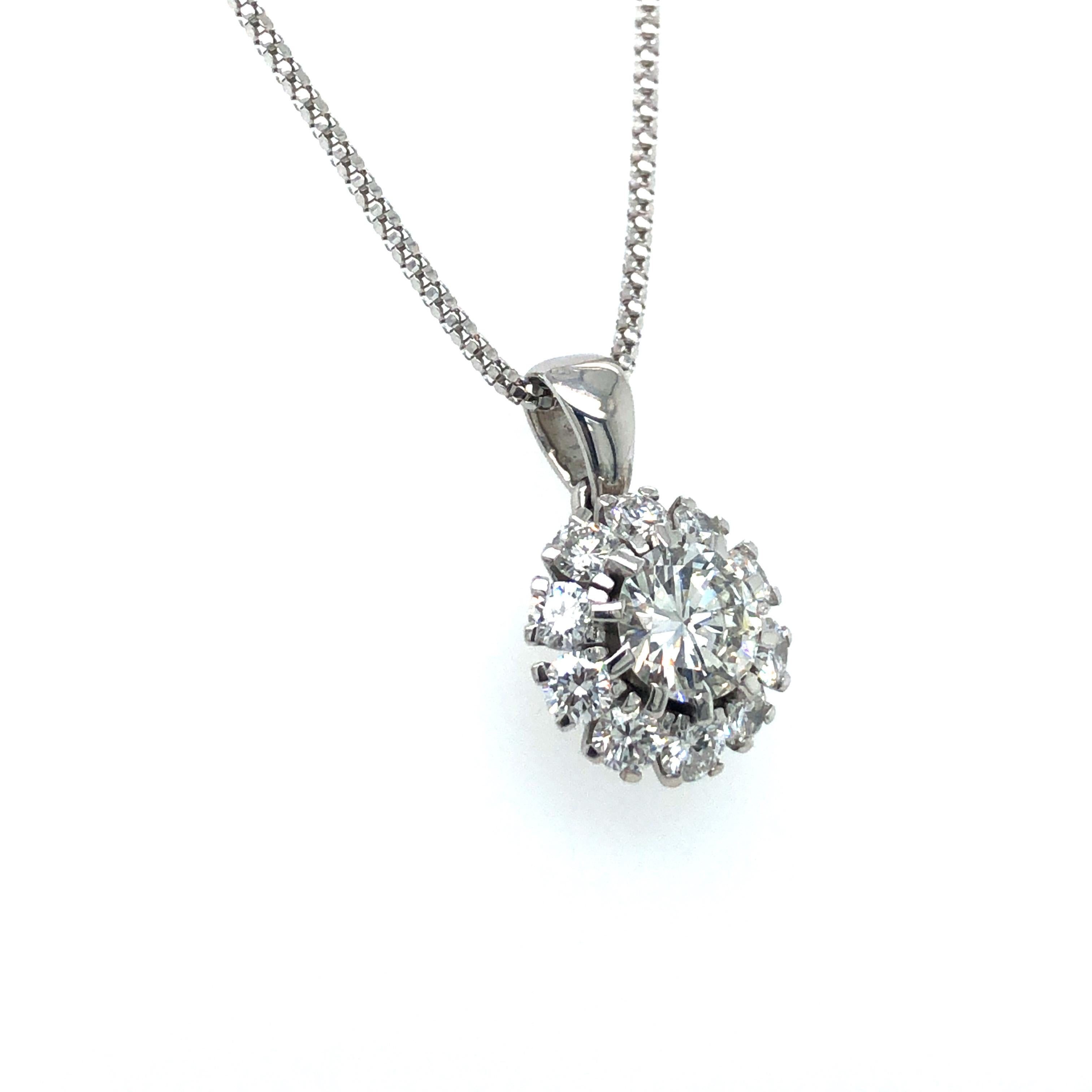 This diamond pendant necklace in 18 karat white gold features a brilliant-cut diamond of approximately 1.10 carats and of G colour and vs1 clarity. Entourage set with 10 brilliant-cut diamonds of G/H colour and vs/si clarity, total weight