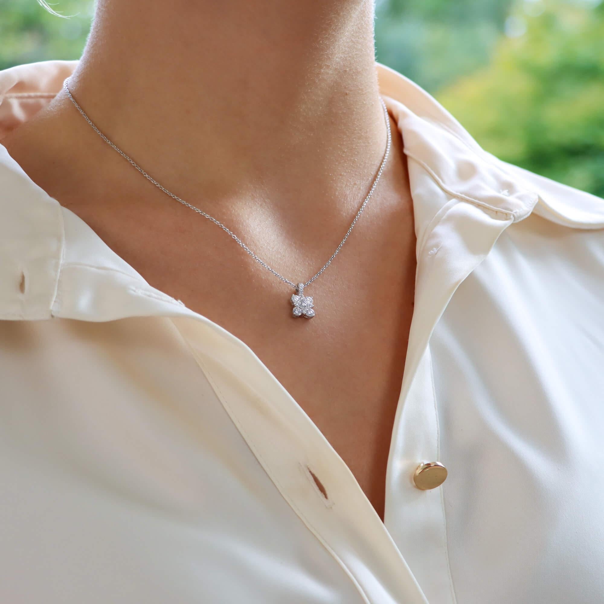This rather stunning pendant contains nine round brilliant-cut diamonds that create the wonderful floral star motif with a diamond set bale to further accentuate the design. 
The central diamond is bezel set with mille grain detailing, four further