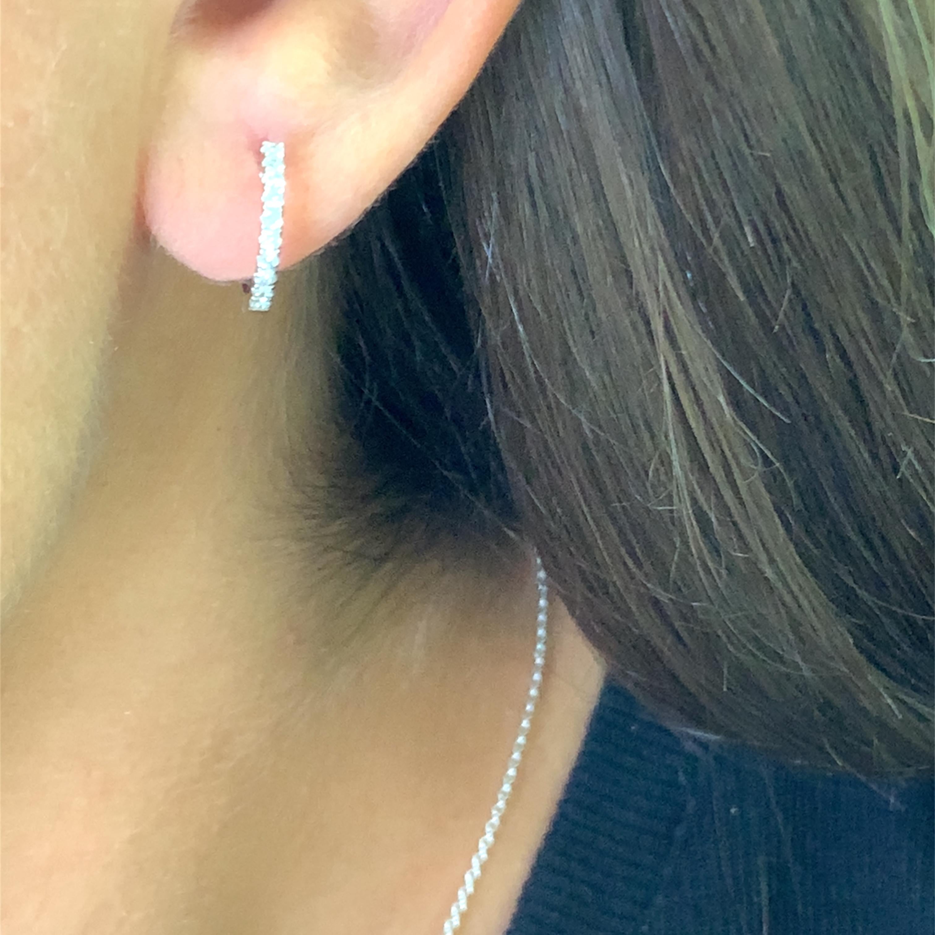 Elegantly crafted hoop earrings in lustrous 18k white gold, each earring is set with a series of round brilliant cut diamonds. These timeless earrings offer a classic silhouette with a touch of sparkle, perfect for adding a refined touch to any
