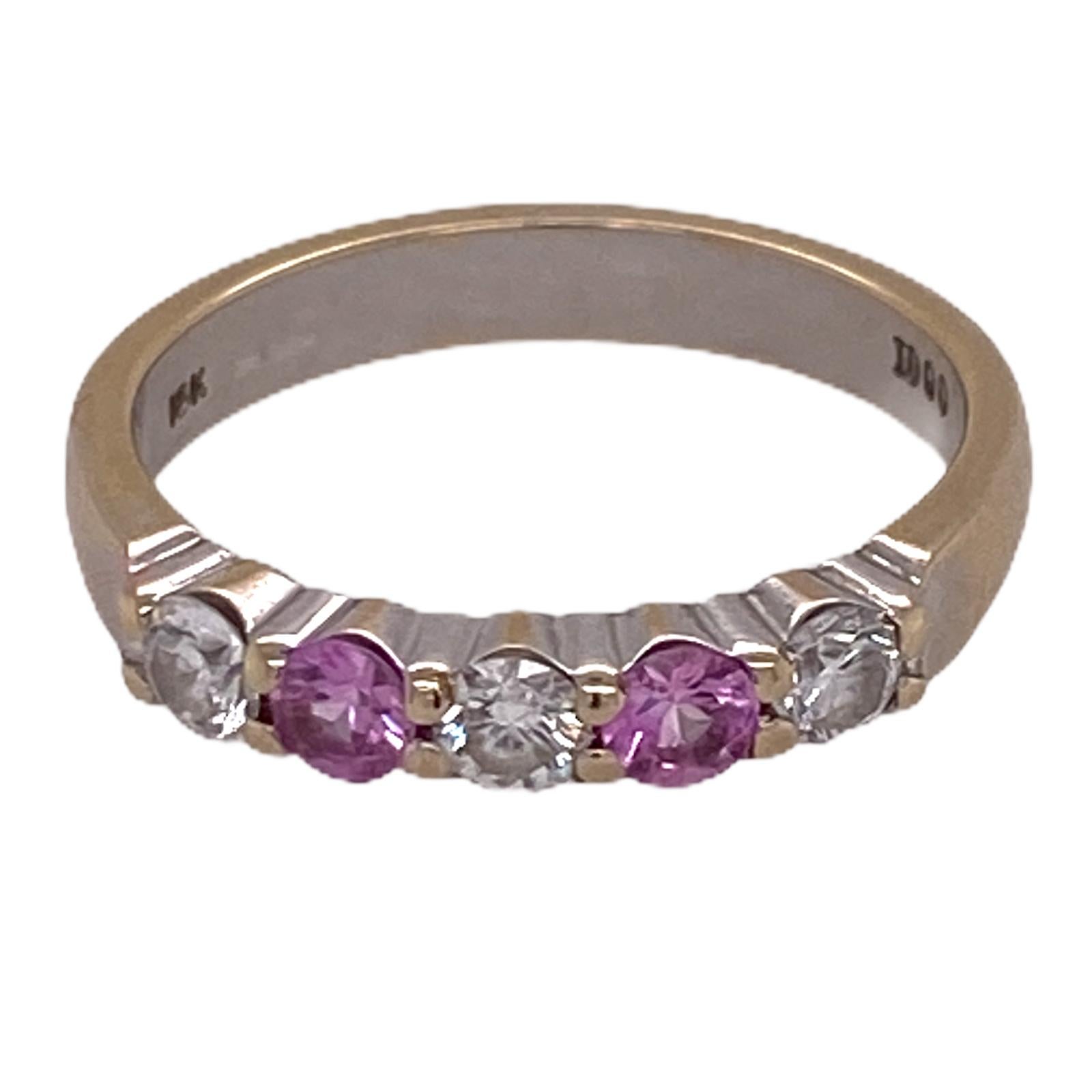 Beautiful diamond and pink sapphire wedding band fashioned in 18 karat white and yellow gold. The band features 3 round brilliant cut diamonds weighing approximately .30 carat total weight and graded H-I color and SI1 clarity. The two pink sapphires