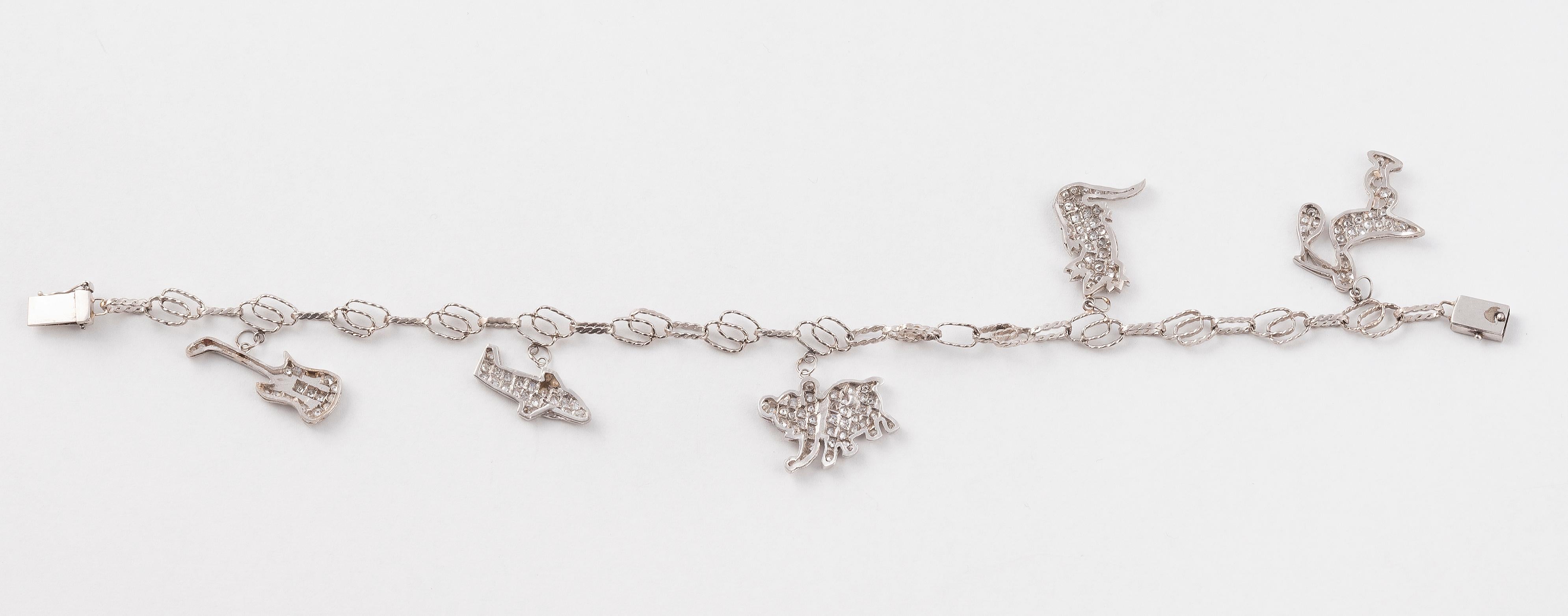 The open-link chain supporting five millegrain diamond set charms depicting various animals and a guitar.
Mounted in Platinum
Length: 18 cm 

Weight: 16 gr