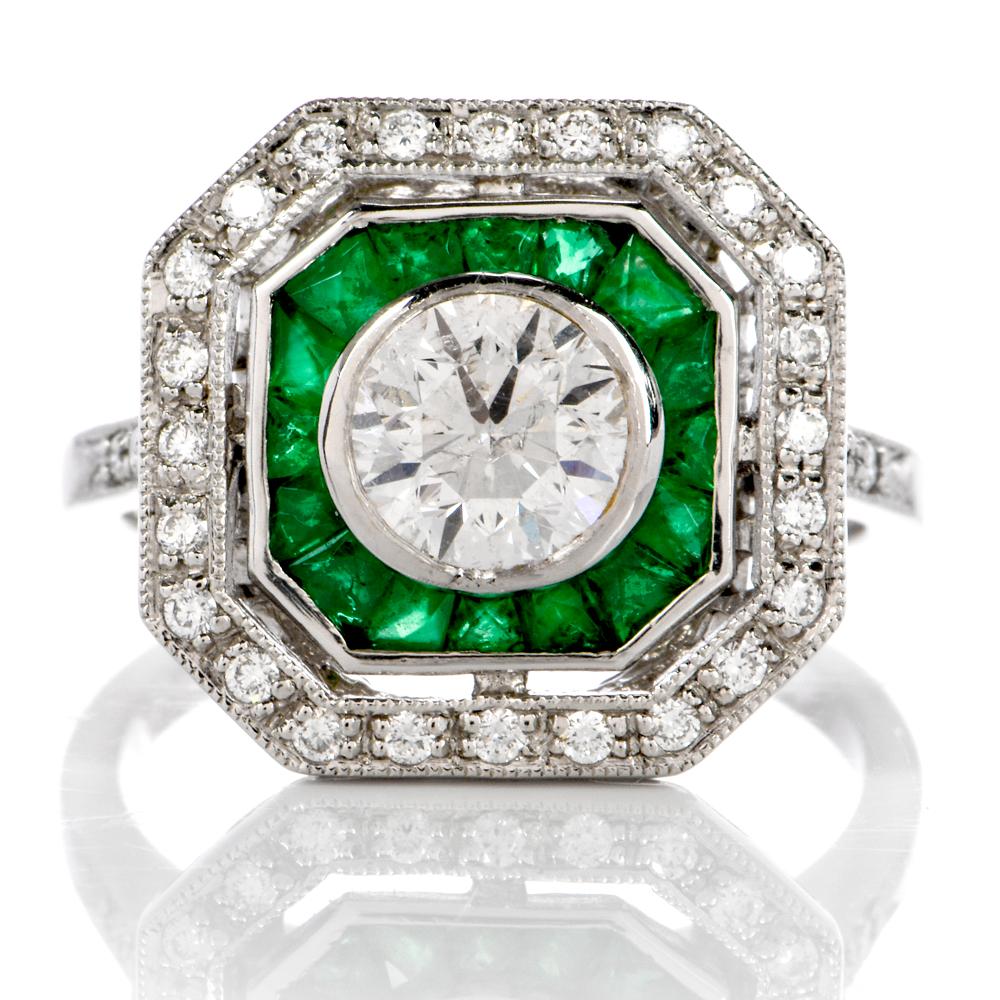 This classic  platinum engagement ring is centered by one round brilliant cut diamond, graded H color/ VS2 clarity and weighing an estimated 1.05 carats. 16 French cut genuine emeralds weighing an estimated 0.85 carats total surround the center