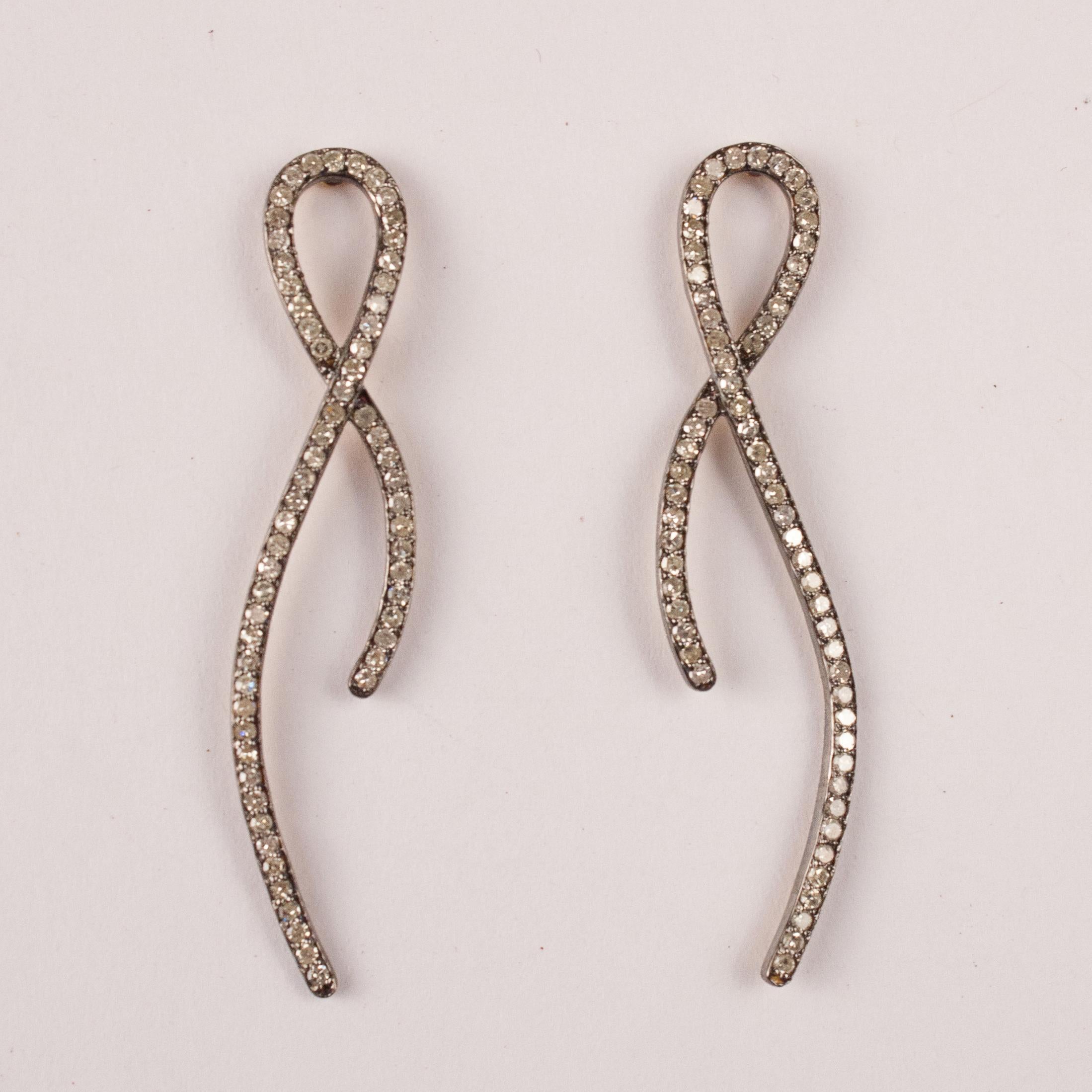 Very wearable diamond dangle earrings with a ribbon design. Each mirror-image earring features 61 flat-cut diamonds pave set in sterling silver with 14-karat gold posts and backs. Earring length is 2 inches.