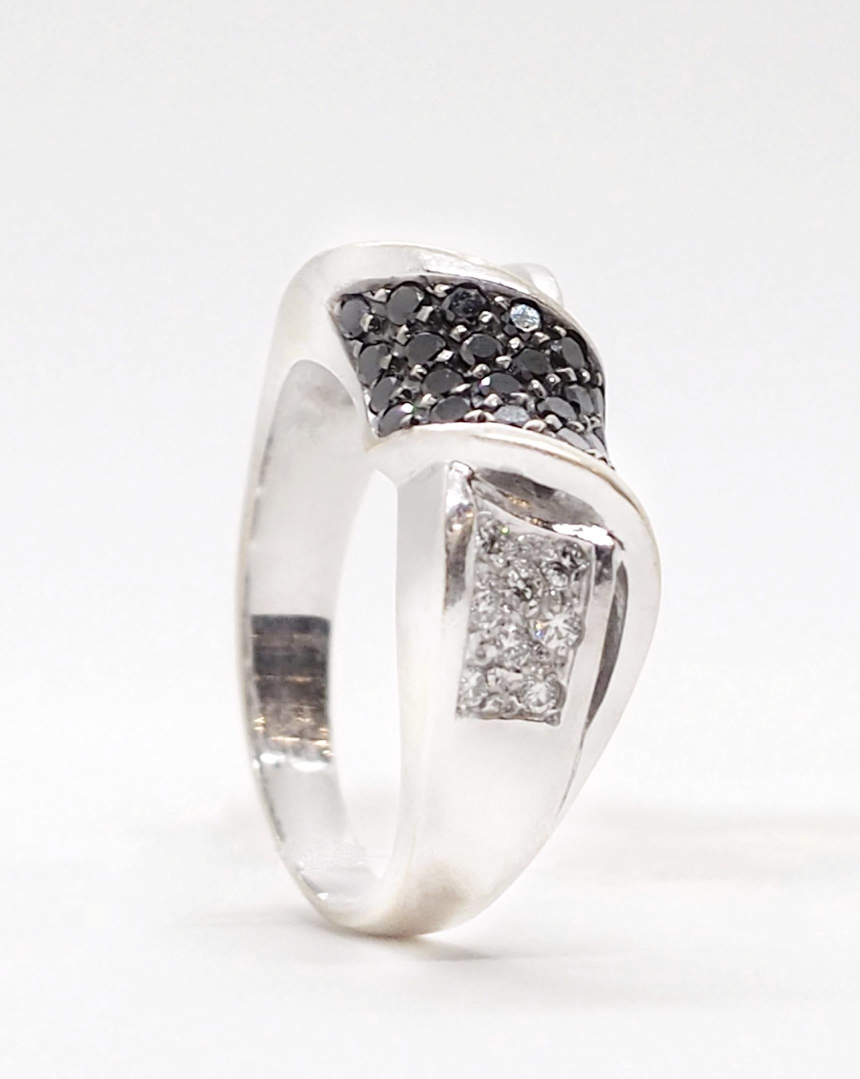 An elegant black and white diamond ring crafted in 18K white gold. It features black (0.8 carat) and white (0.5 carat) diamonds. The central part of the ring is represented by a bow paved with bi-color diamonds. The ring goes well with any outfits