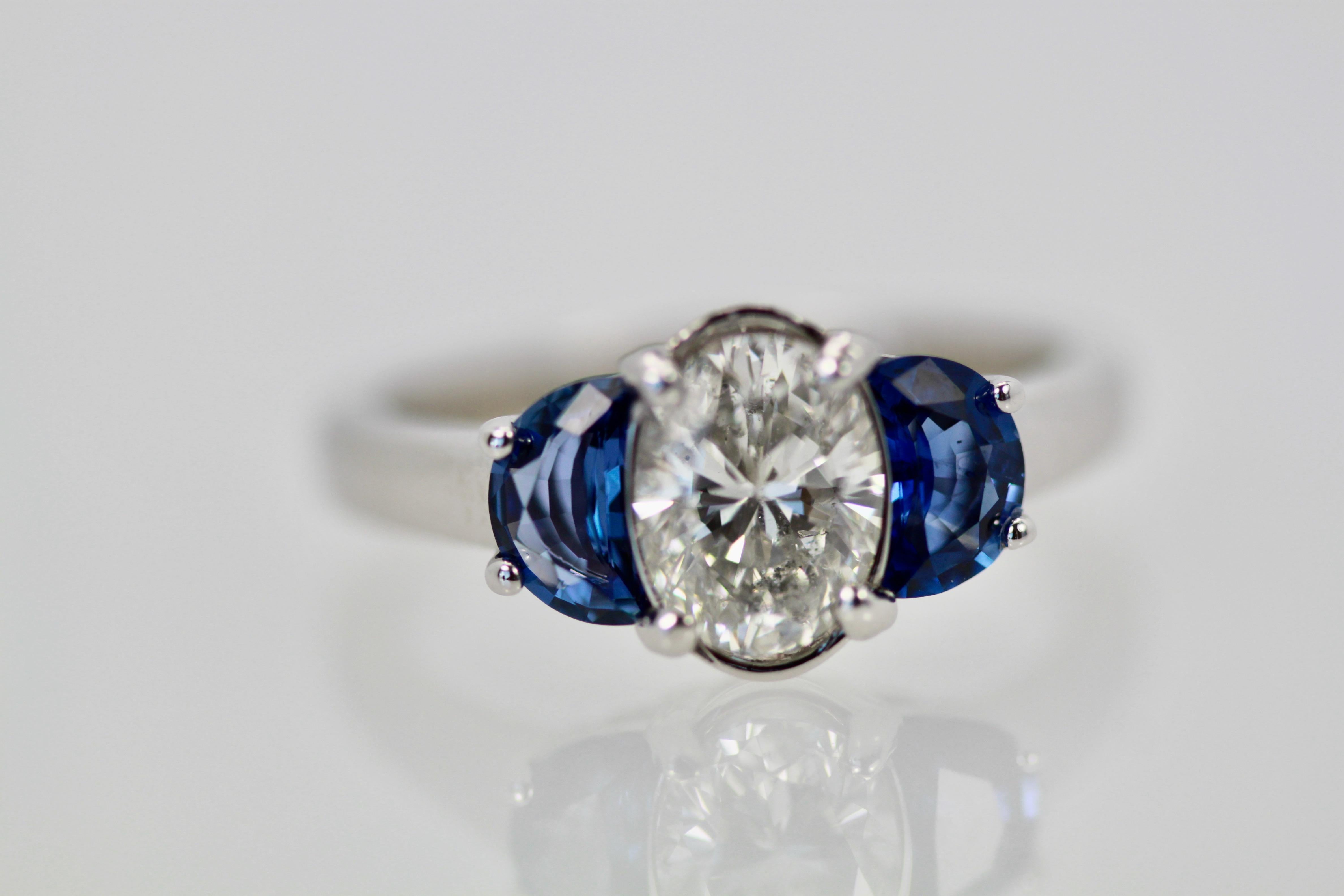 This ring is unusual as it has a center oval cut Diamond of 1.20 carats and enhanced by moon cut Sapphires of 1/2 carat each totaling 2.20 tcw.  The ring is sized 6 1/4 and can be enlarged or made smaller.  It weighs 4.8 grams.  This ring is perfect