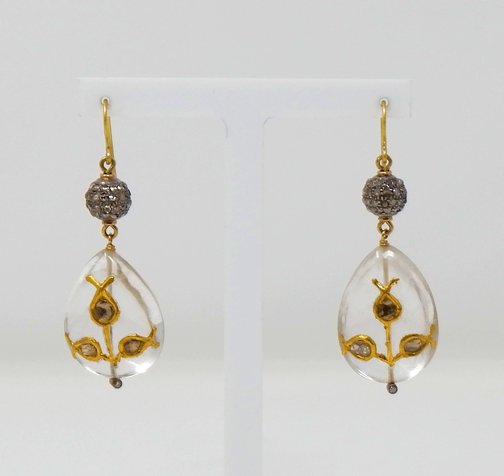 A pair of charming, hand made 18 karat gold and silver diamond earrings. Two unusual and precious rock crystal drops are set with foil backed Indian cut diamonds in the Mughal tradition which is often seen in museums the world over. The delicate and