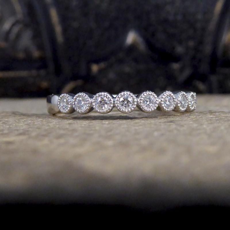 This brand new has never been worn and is the perfect wedding or stackable ring. A beautiful half eternity ring that sparkles across the whole of the finger with 12 Modern Brilliant Cut Diamonds in a collar setting with a milgrain edge in 9ct White