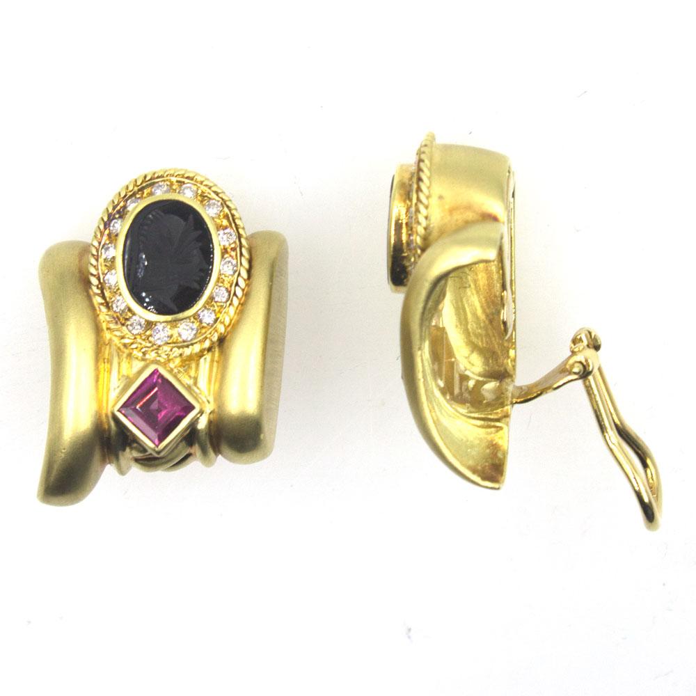 These beautiful 18 karat brushed yellow gold earrings feature diamonds, rubelite gemstones, and onyx intaglio. There .60 carats of round brilliant cut diamonds surrounding the onyx intaglio. The earrings feature clip backs and are signed JBS. They