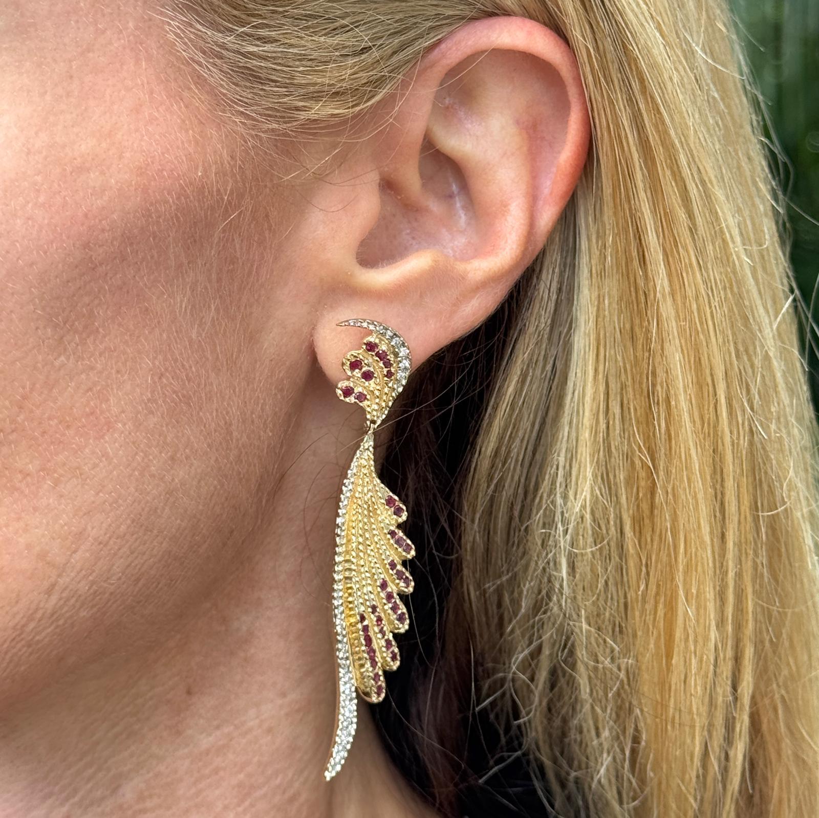 Ohrringe aus 14 Karat Gelbgold mit Erté-Diamanten und Rubinen, besetzt mit 38 runden Diamanten im Brillantschliff von insgesamt ca. 0,60 Karat, Farbe H-I und Reinheit SI. Glänzende Rubin-Akzente bilden einen lebhaften Kontrast zum warmen Gold und
