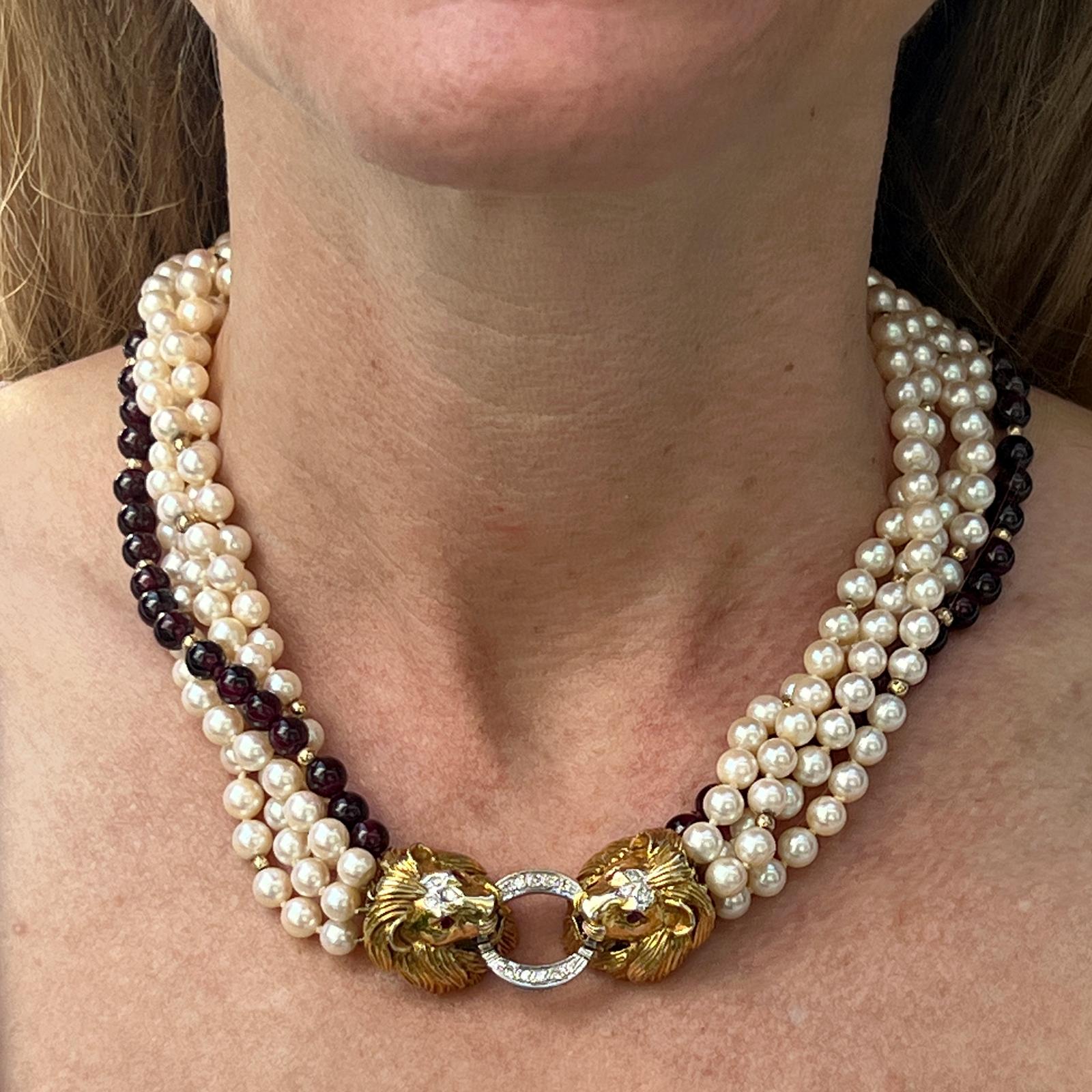 Diamond and ruby double lion head clasp necklace fashioned in 14 karat yellow gold. The clasp features 16 round briliant cut diamonds weighing approximately .25 carat total weight and graded H color and VS2-SI1 clarity, ruby eyes. The clasp measures