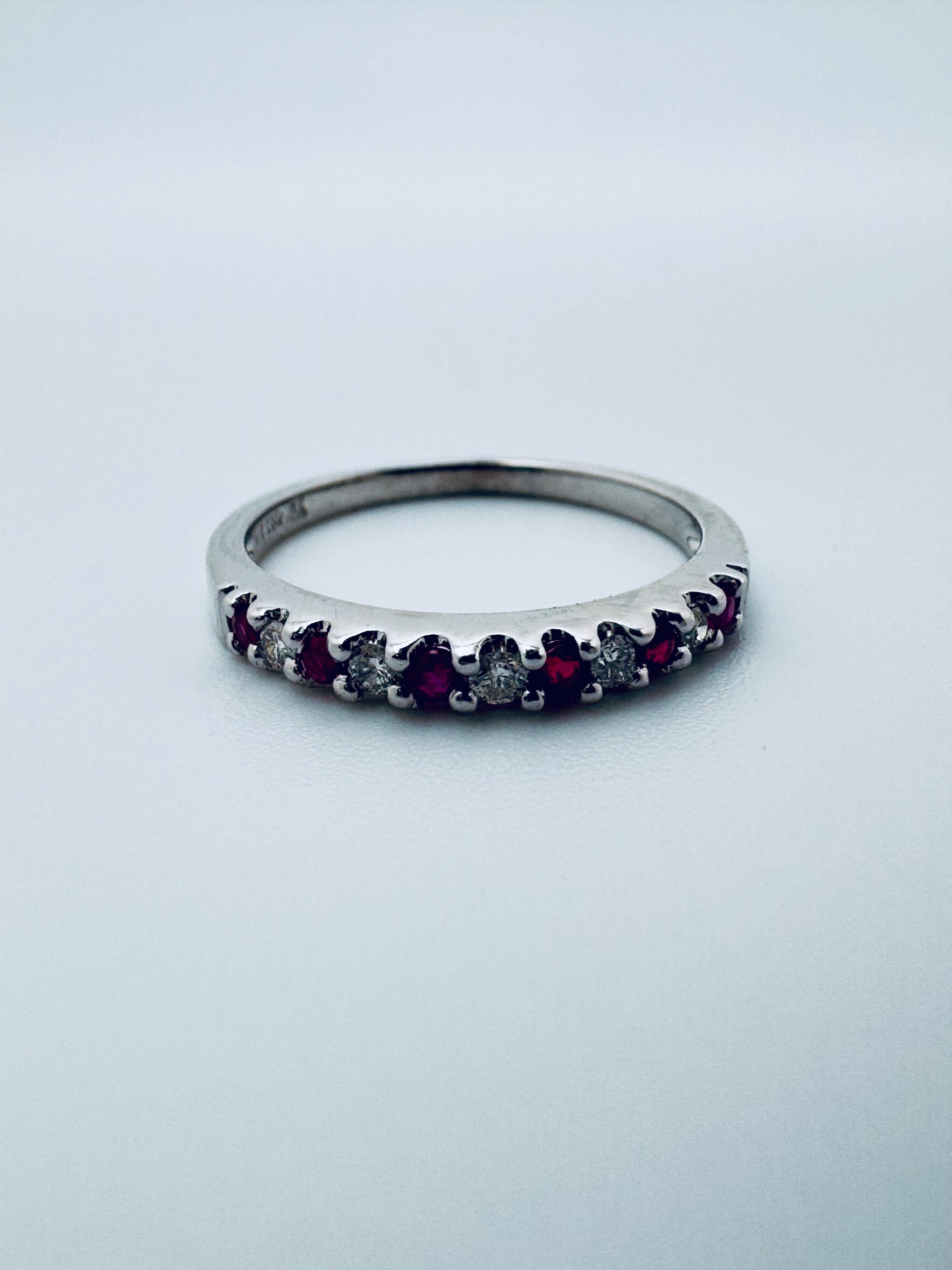 This elegant 14K white gold ring features a timeless alternating pattern of vibrant rubies and sparkling diamonds. Each gemstone is expertly set in a sleek band that highlights their contrasting brilliance and color. The ring showcases a total carat