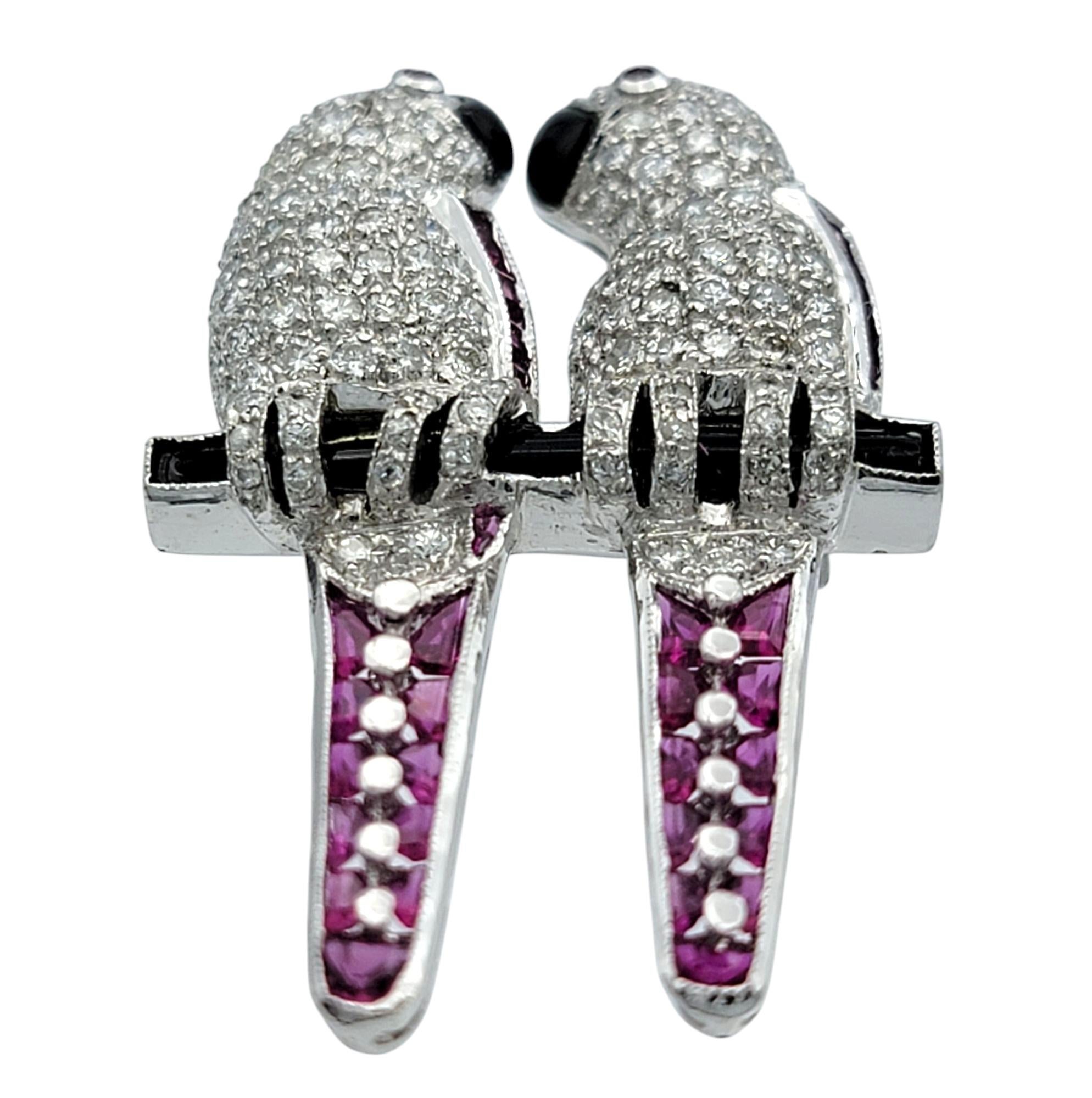 Este exquisito broche es una obra maestra de artesanía, con una deslumbrante combinación de diamantes, rubíes y ónice engastados en oro blanco de 18 quilates. El encantador diseño muestra a dos tortolitos posados juntos, con intrincados detalles, y