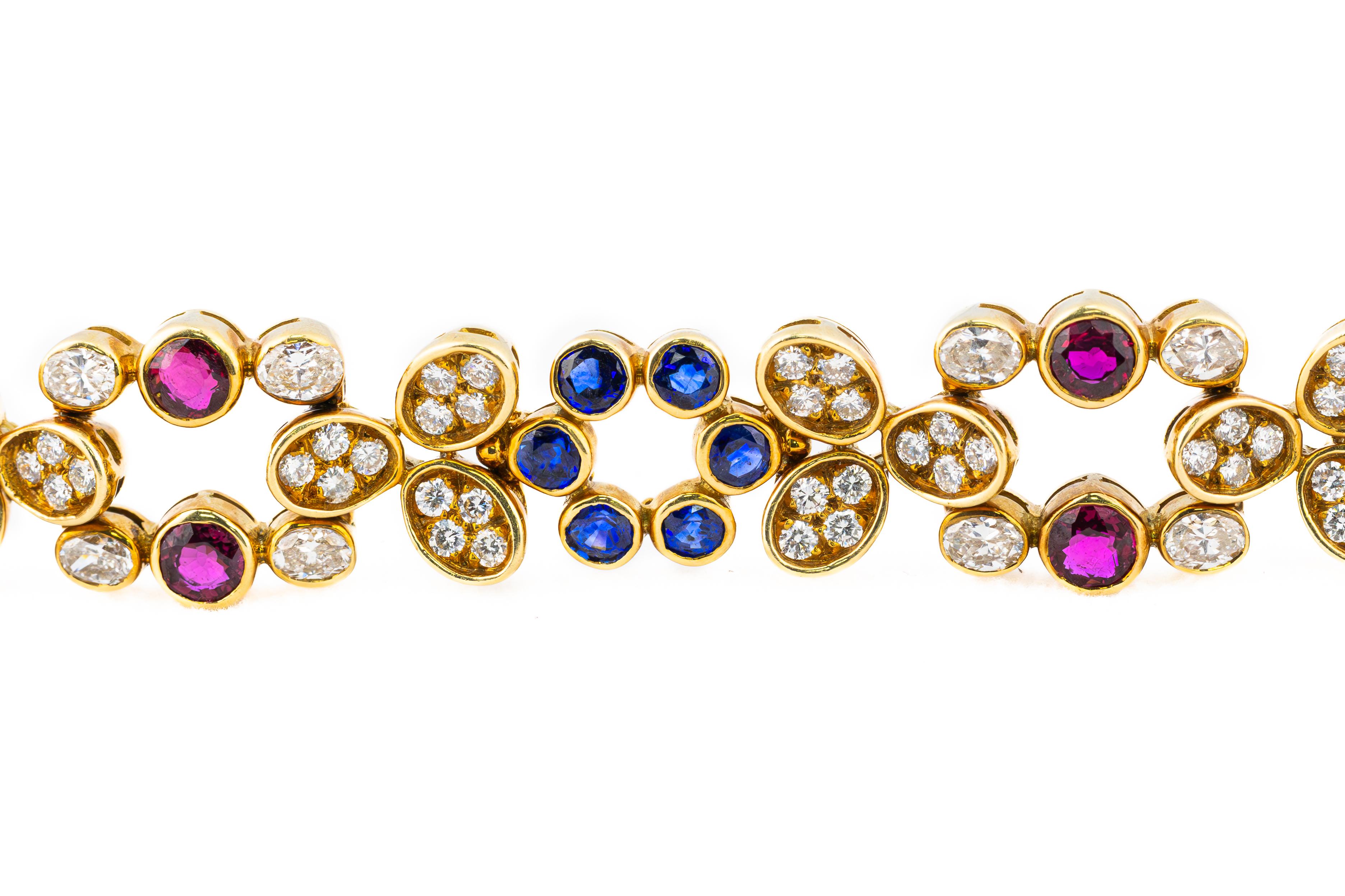 Diamond, Ruby, and Sapphire Gold Floral Bracelet

Description: A vibrant expression of artistry and elegance, this exquisite bracelet is a dazzling composition of diamonds, rubies, and sapphires, all set in the warmth of 18K yellow gold. Designed in