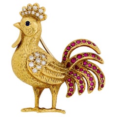 Épingle en or jaune 18 carats ornée d
un coq en diamant, rubis et saphir