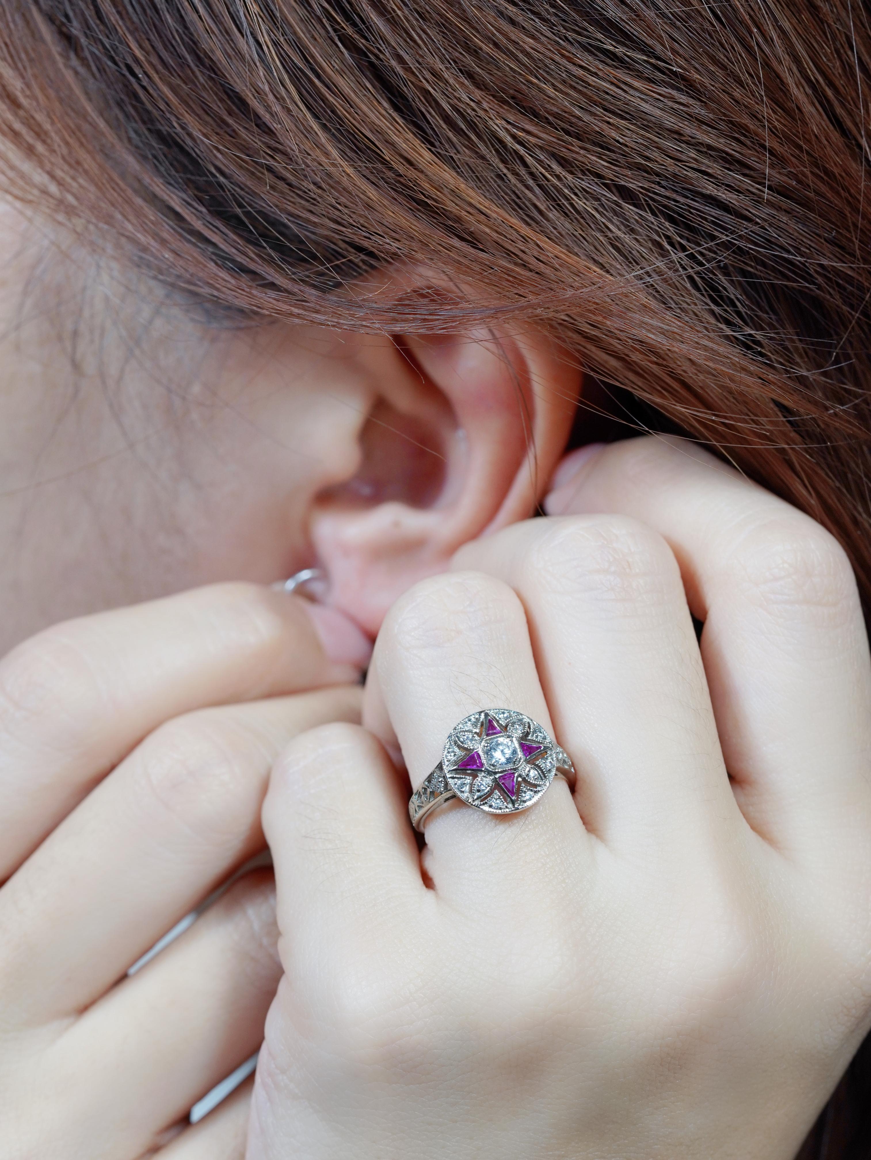 This captivating Art Deco-style floral ring features a brilliant diamond at the center, radiating timeless elegance. Surrounding it are vivid triangle-shaped rubies, positioned at the top, bottom, left, and right forming a striking star or
