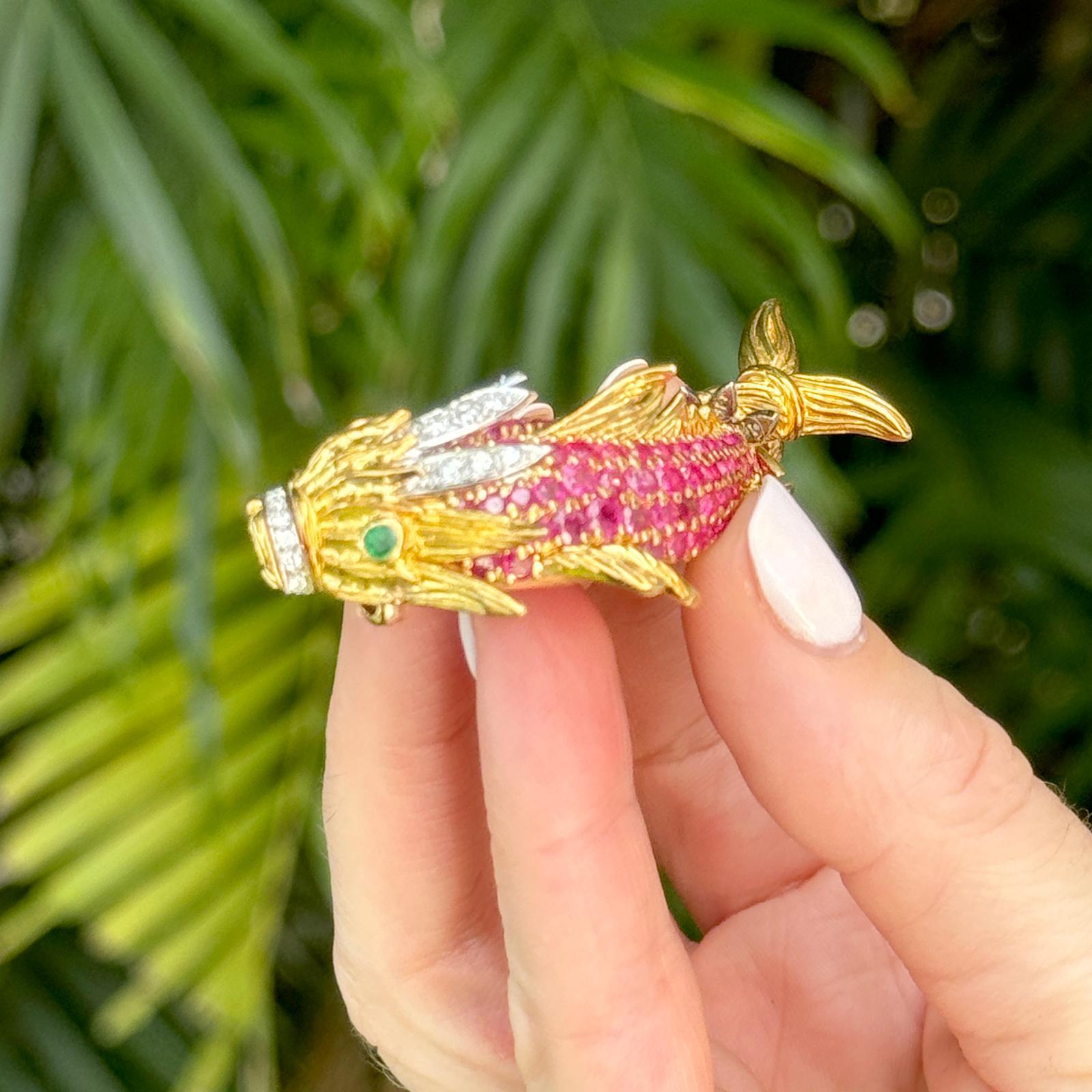 The Diamond, Ruby, and Emerald Dragon Fish Brooch is a captivating piece that showcases exquisite craftsmanship and rich symbolism. Crafted from luxurious 18 karat yellow gold, this brooch features an intricately detailed dragon fish adorned with 31