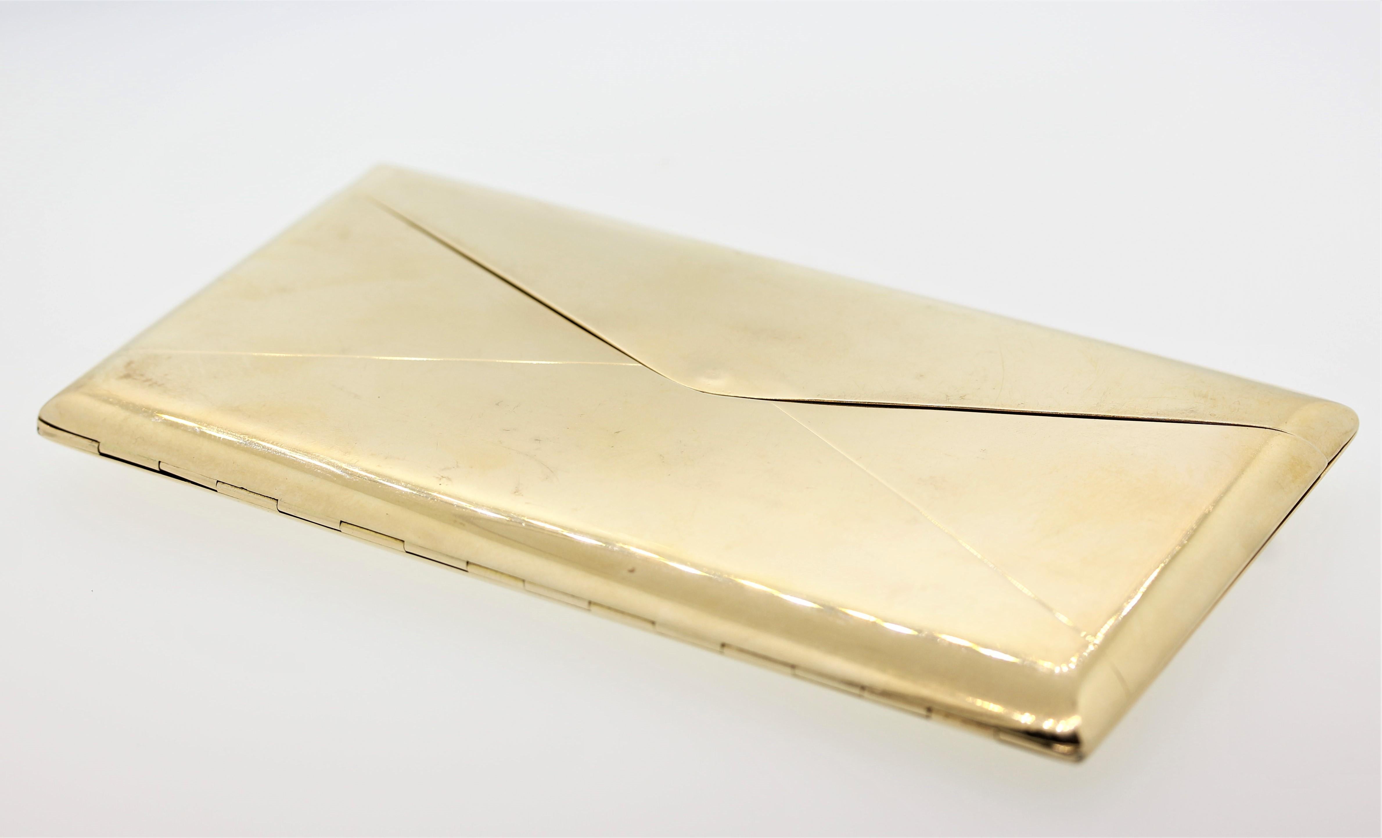 Das 14-karätige Goldgehäuse in Form eines Briefumschlags ist mit Diamanten im Baguetteschliff und Rubinen im Kalibré-Schliff verziert, die in die Initialen 