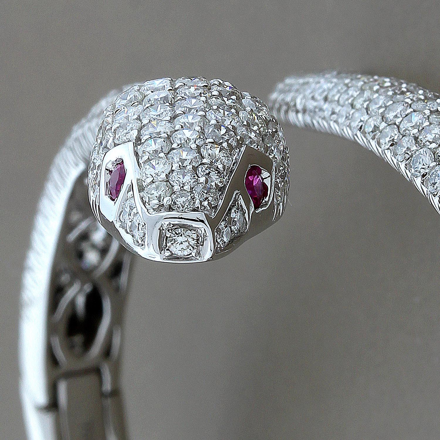 A sexy and sleek piece, this cuff bracelet features 6.74 carats of VS quality round cut diamonds set in 14K white gold. The surreal snake has two ruby eyes for a captivating look.
Both the head and tail move open to allow an easy wear. 
Fits most
