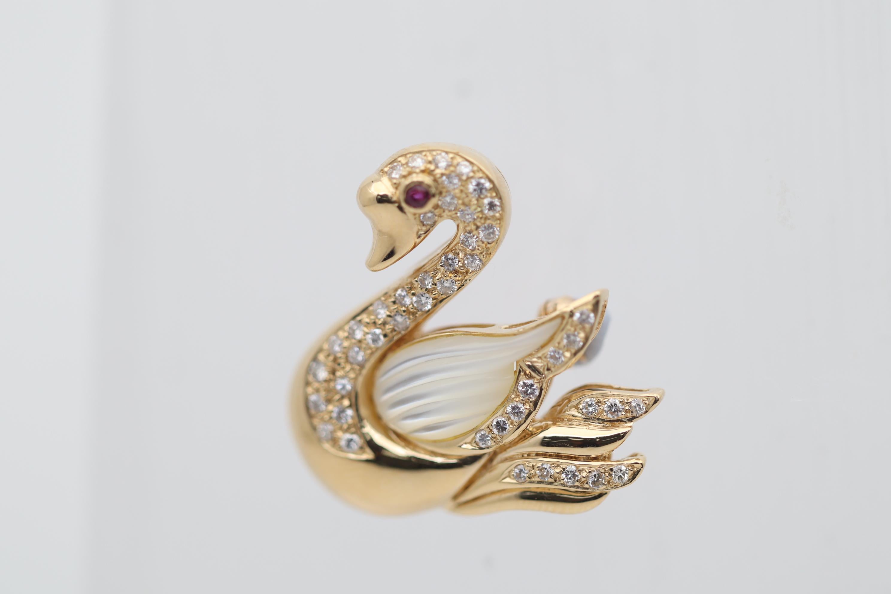 A sweet and stylish pin featuring a bedazzled gold swan! It features 0.45 carats of round brilliant-cut diamonds set around the swan’s body along with a single ruby set as its mesmerizing eye. Its wing is made from a hand-carved piece of mother of