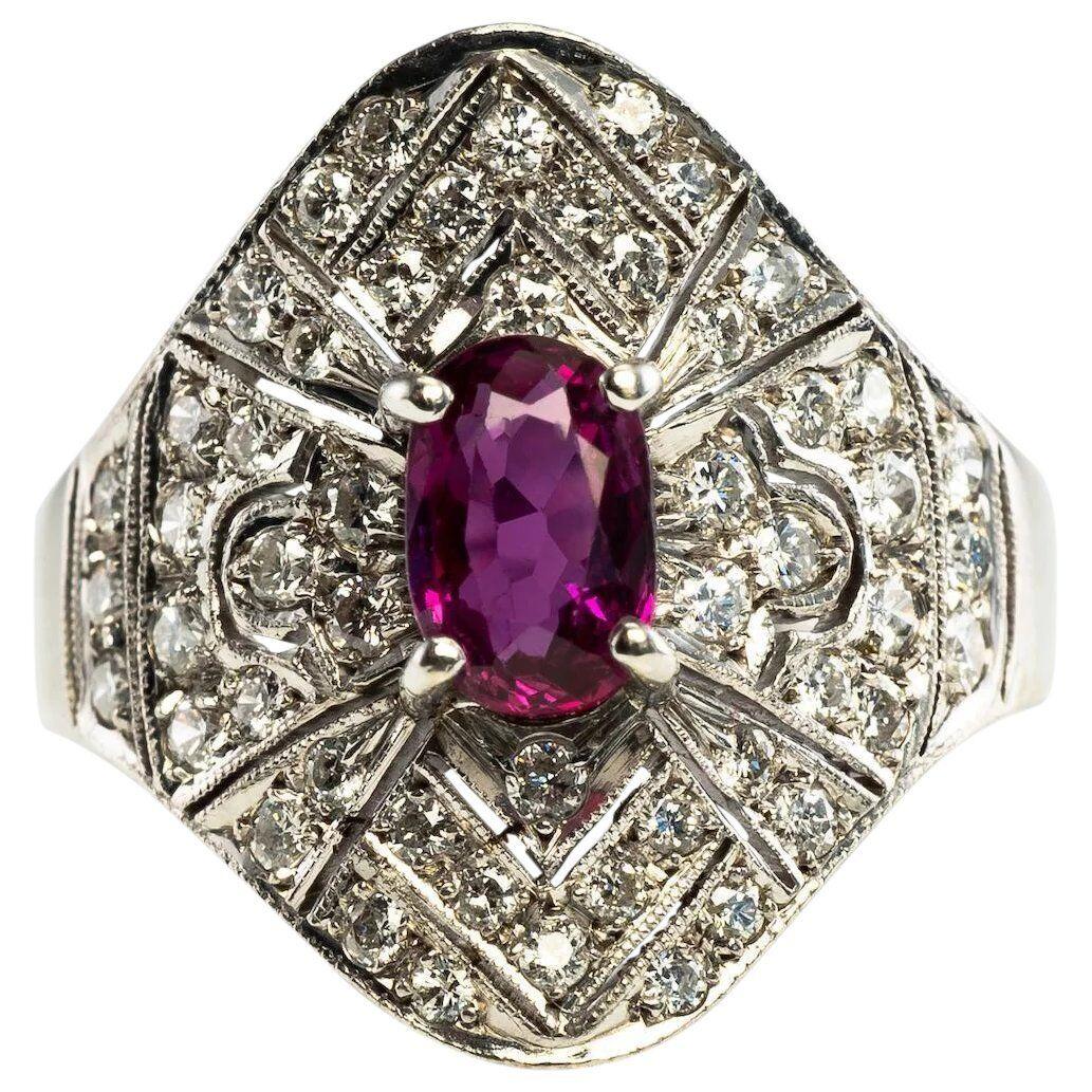 This pretty vintage ring is finely crafted in solid 14K White Gold and set with genuine Earth mined Ruby and Diamonds. The center oval cut Ruby measures 6mm x 4mm (.60 carat) and this is a very clean and transparent gem of great intensity and strong