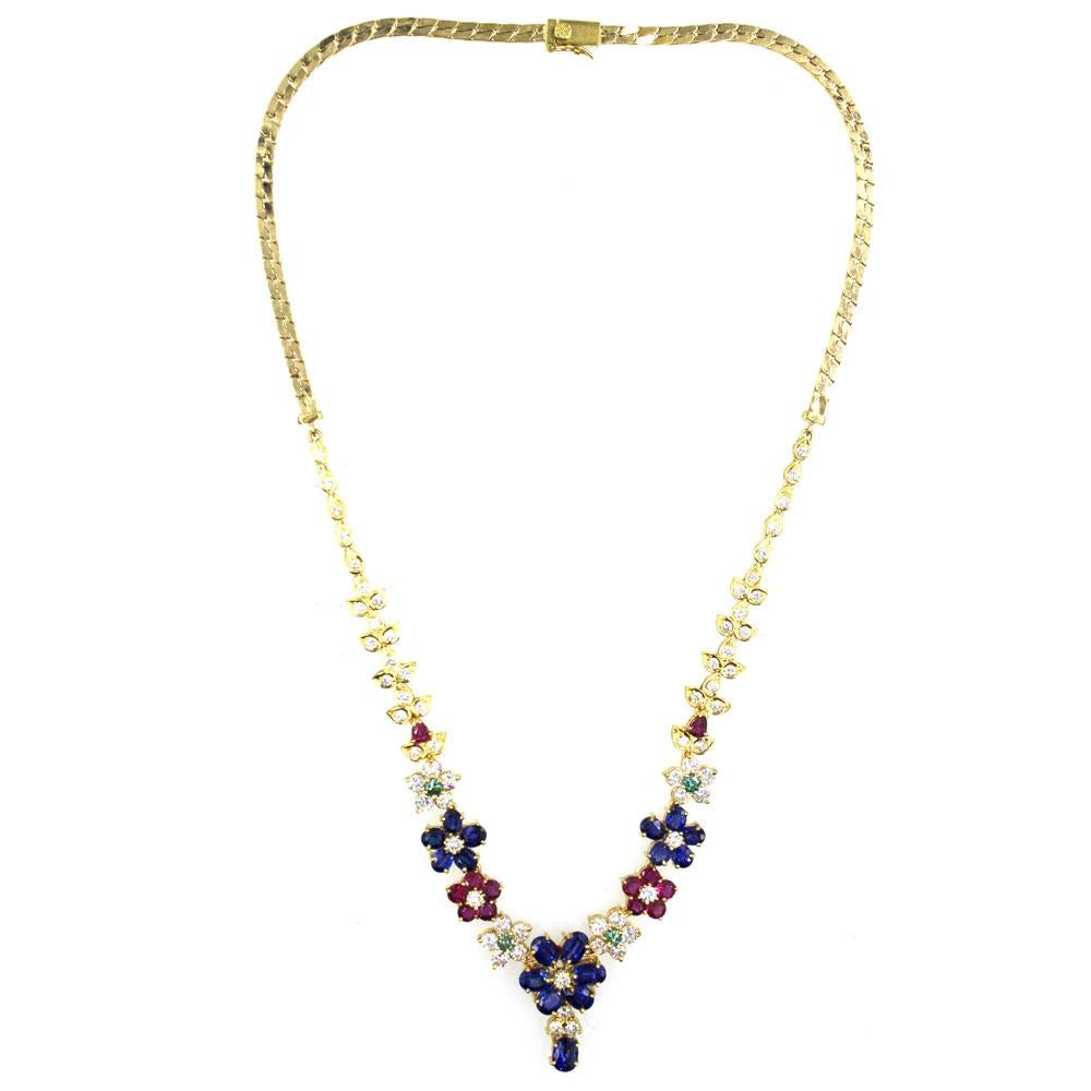 A colorful array of rubies, sapphires, and emeralds are set with diamonds in this beautifully designed floral necklace. Fashioned in 18 karat yellow gold, the necklace features 3.60 carat total weight of round brilliant cut diamonds graded G color