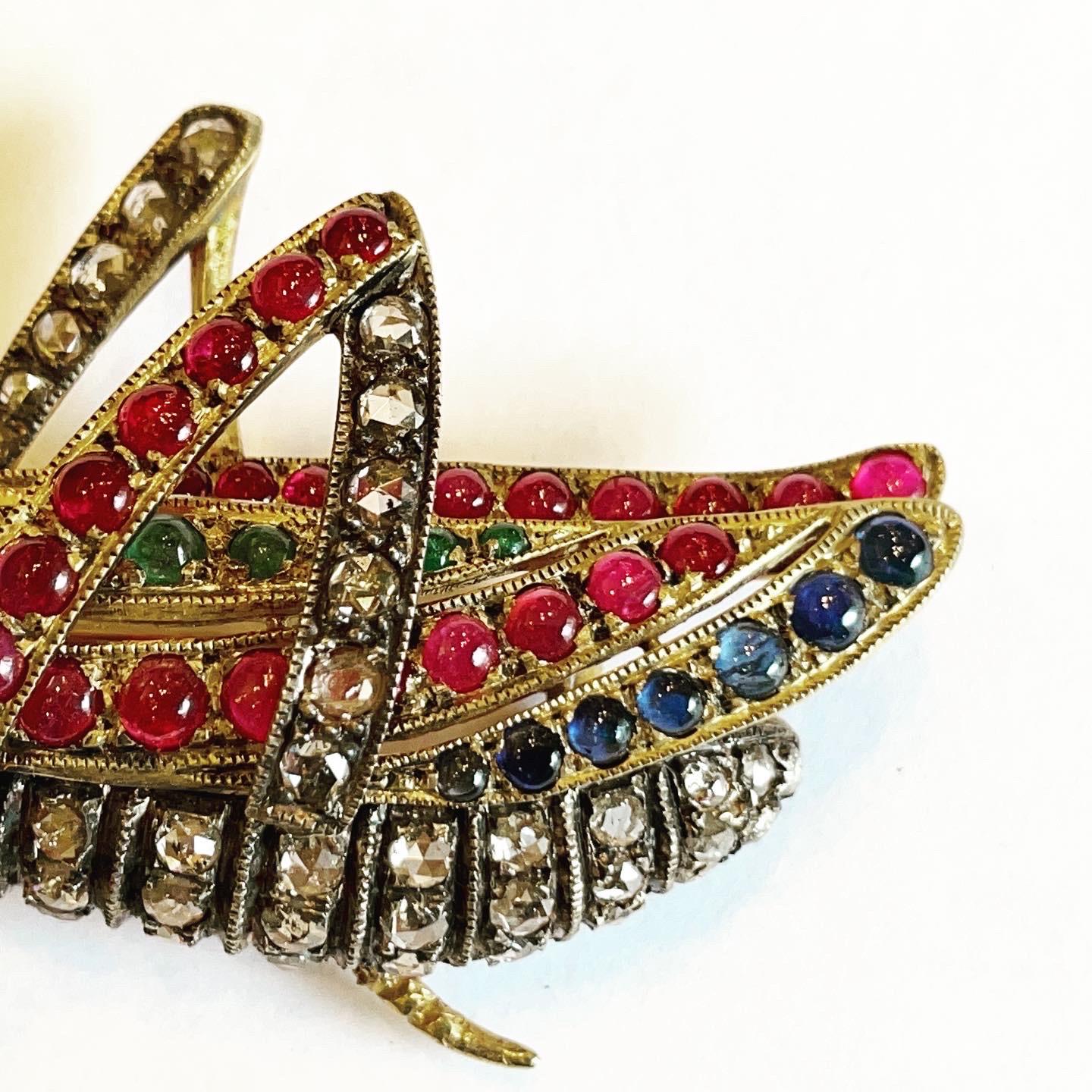 Grasshopper or Cricket form brooch-pendant, set with rose cut diamonds and cabochon sapphires, emeralds and rubys.
Total aproximated diamonds weight: 2.25 carats.
Total aproximated rubys weight: 2.2 carats.
Total aproximated sapphires weight: 0.85