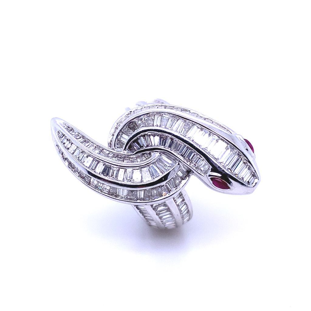 A diamond and ruby snake ring in 18 karat white gold.

This truly bold statement ring is channel set throughout with baguette cut and tapered baguette diamonds especially cut to fit the form of a coiled snake.

Its head is bezel set with two rich