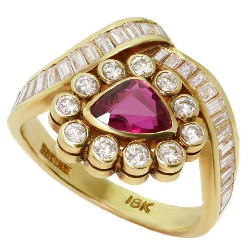 This stylish vintage rign is made in 18k yellow gold and set with a vivid red faceted triangular heat-treated ruby of an estimated 0.70 carats, 29 baguette-cut channel-set diamonds of an estimated 1.14 carats, and 11 round bezel-set diamonds of an