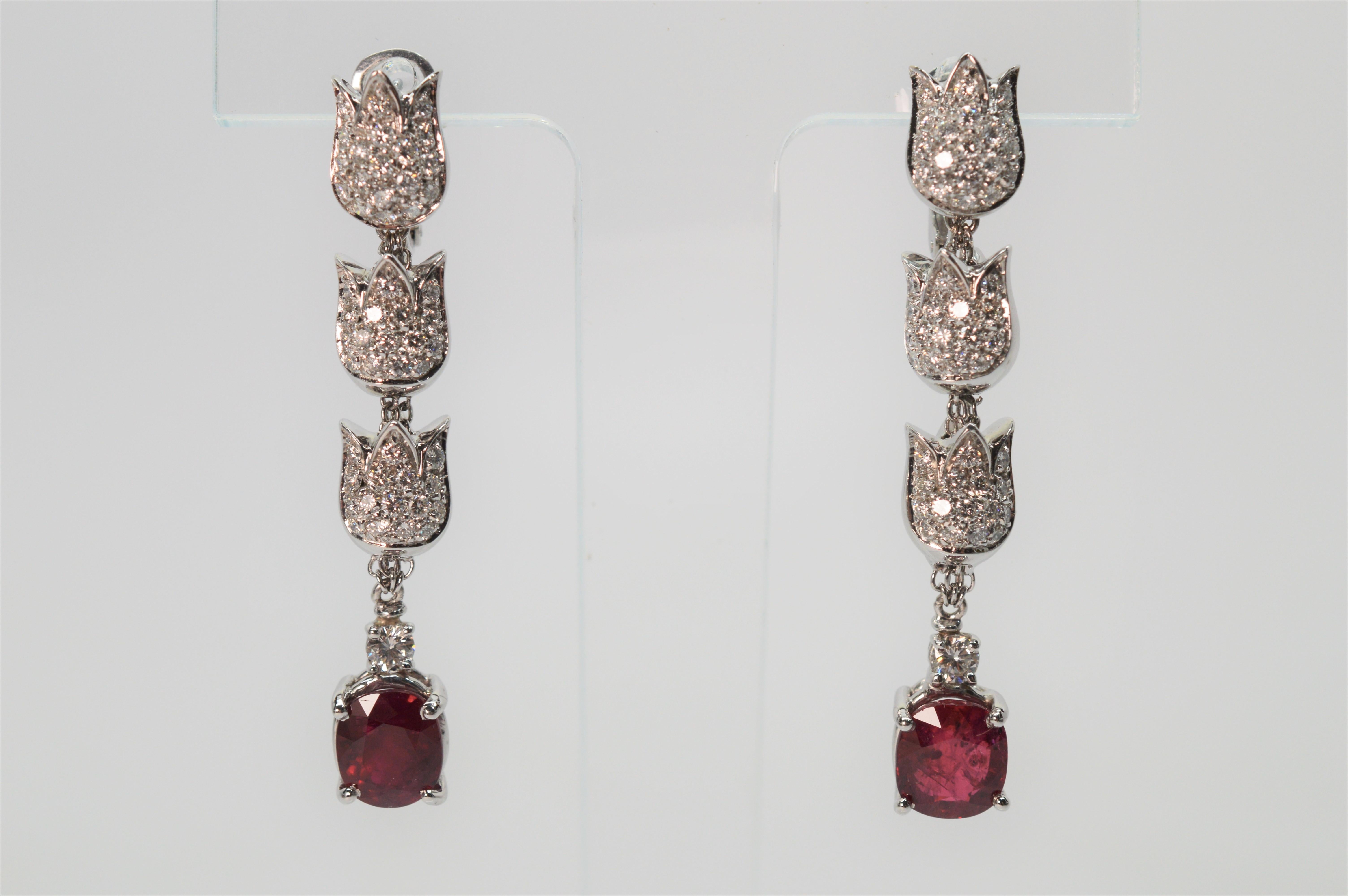Dramatic diamond covered floral inspired triple drops in eighteen karat 18K white gold leads to vibrant rich red prong-set rubies on this elegant and unique earring pair by Mikawa.
White gold tulip shaped links sparkle with over 2.75 carats total