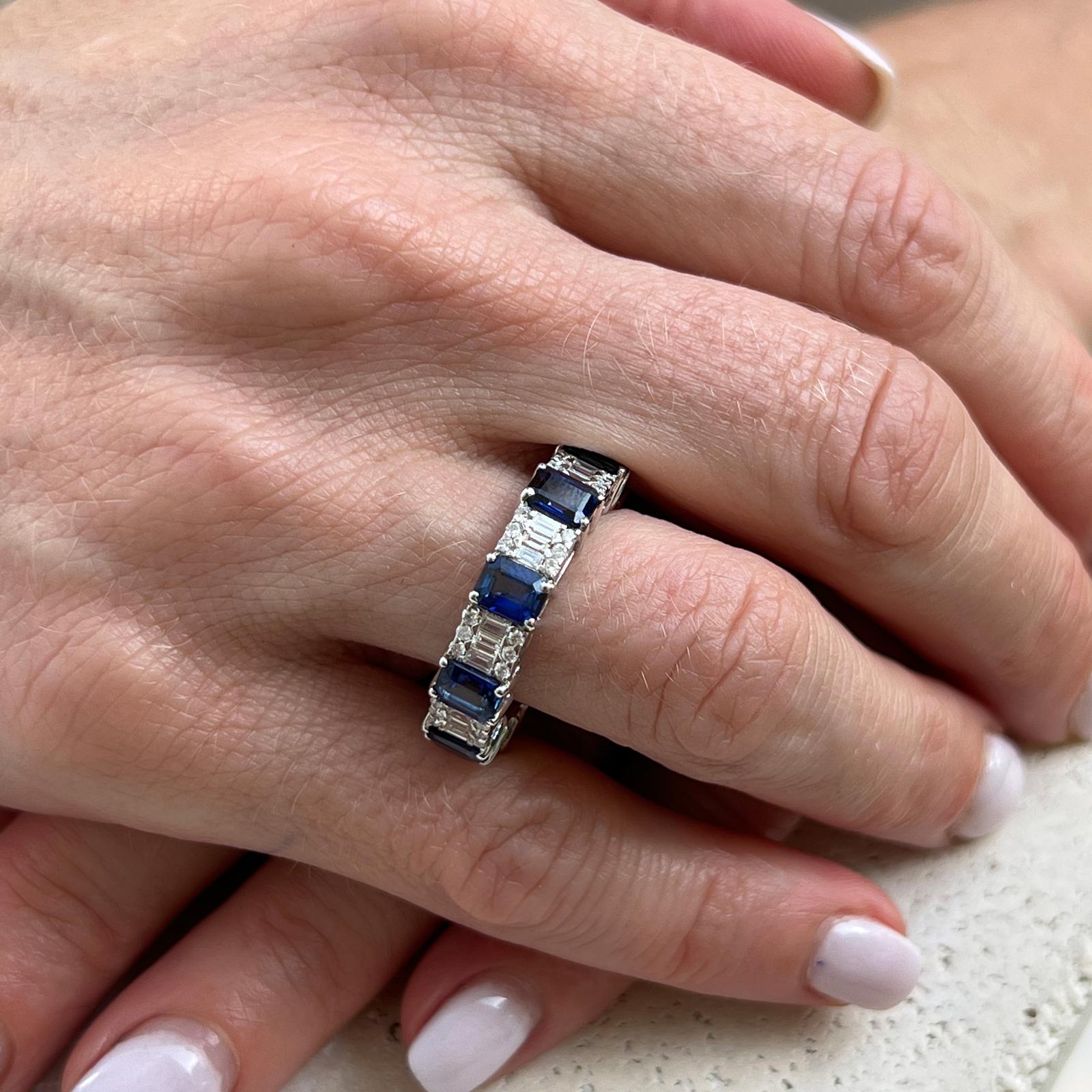 Beautiful diamond and sapphire eternity band crafted in 18 karat white gold. The band features rectangular cut natural sapphires weighing 4.50 CTW. The sapphires alternate with round brilliant and baguette shape diamonds weighing approximately 1.00