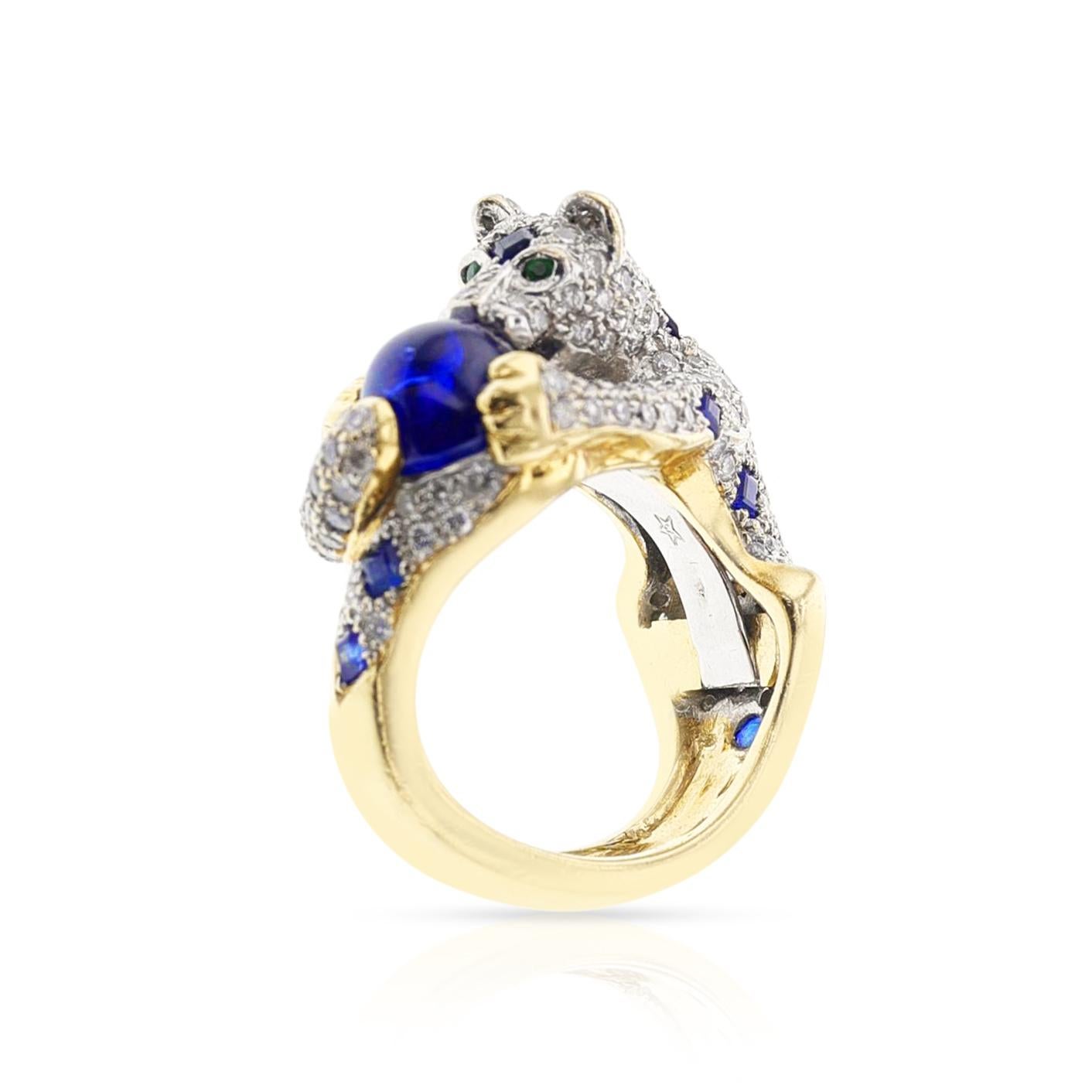 A Diamond, Sapphire, and Emerald Panther Ring in 18 Karat Gold. The Panther is holding a sapphire, and the eyes are Emerald. The sapphire weighs 6.45 carats, and the diamodns weigh 3.60 carats. The total weight is 22.09 grams. Ring Size US 6.25.