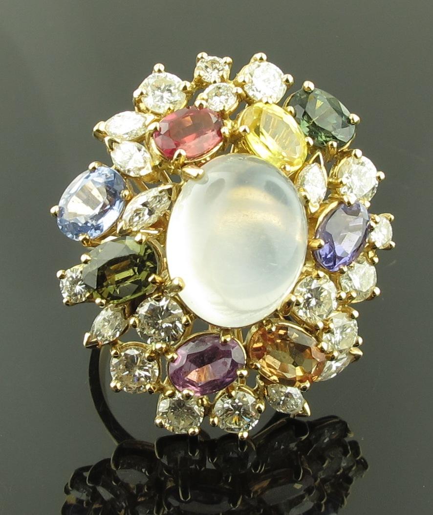 A 9.50 oval shaped center Moon Stone with 8 multi-colored sapphires, weighing 8 carats and 21 diamonds weighing 3.90 carats, set in 14 karat yellow gold.  Ring Size 8.25