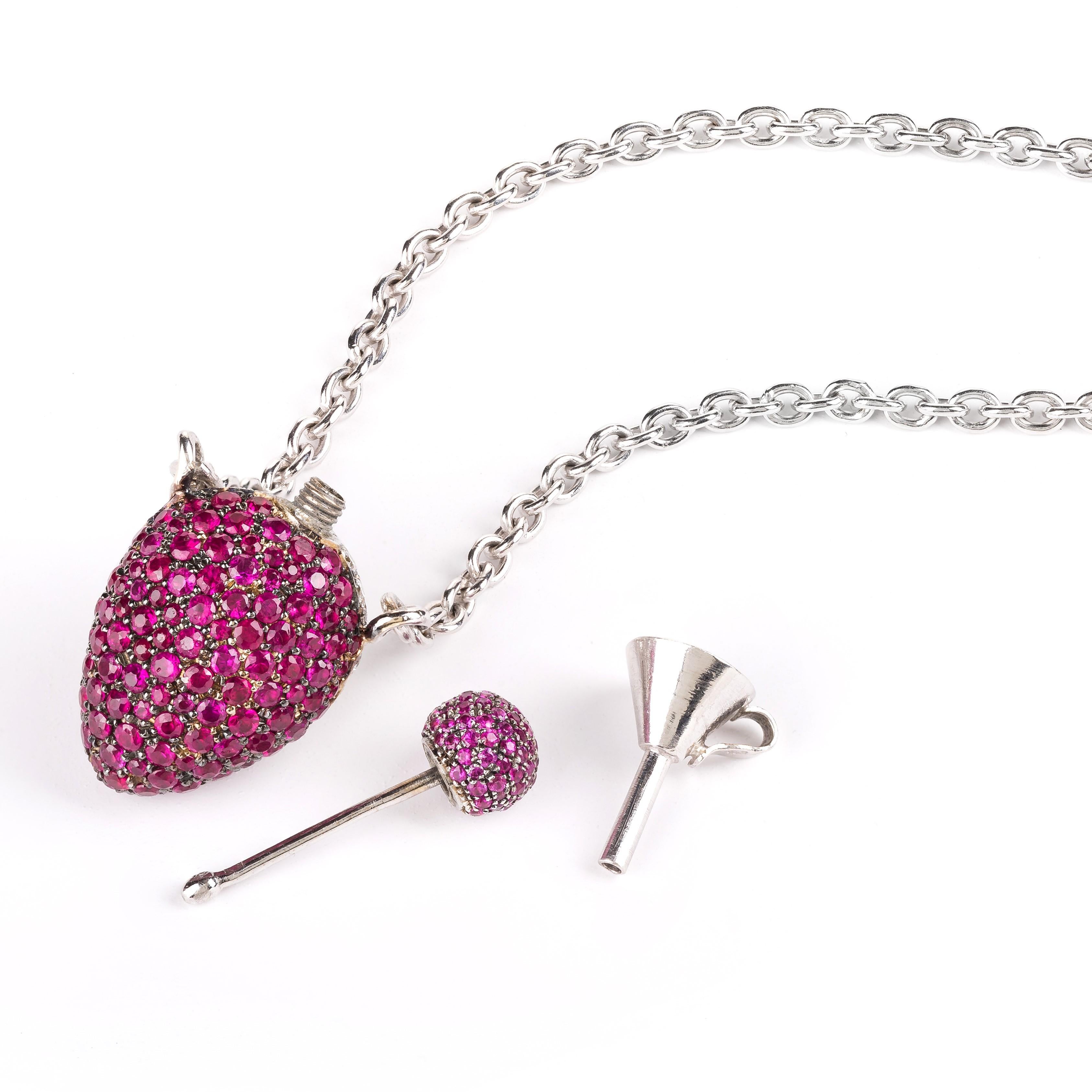 Rosior by Manuel Rosas 19,2k White Gold “Parfum Bottle” Pendant Necklace. 
It is set with Diamonds and Pink Sapphires from one side and just Pink Sapphires from the other.
Total of:
- 98 Pink Sapphires with 0,88 ct; 
- 156 Rubis with 3,31 ct; 
- 64