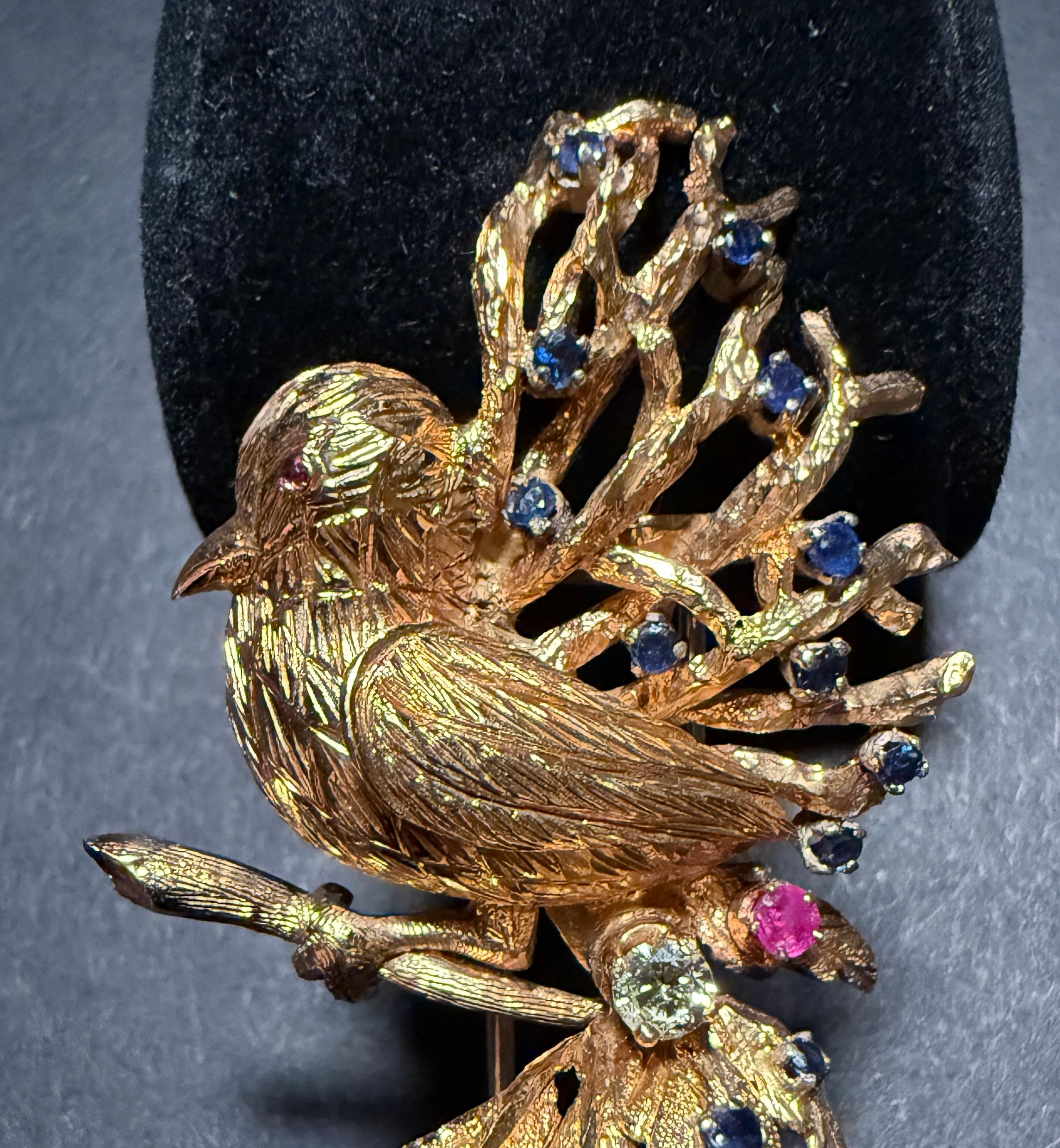 18K yellow gold bird brooch pin with diamond, blue sapphires and rubies. Beautiful hand chased bird nestled among leaves and branches highlighted by sparkling gemstones.
18 blue sapphires
.15ct diamond.
Tested 18K gold.
Weight 27.8g.