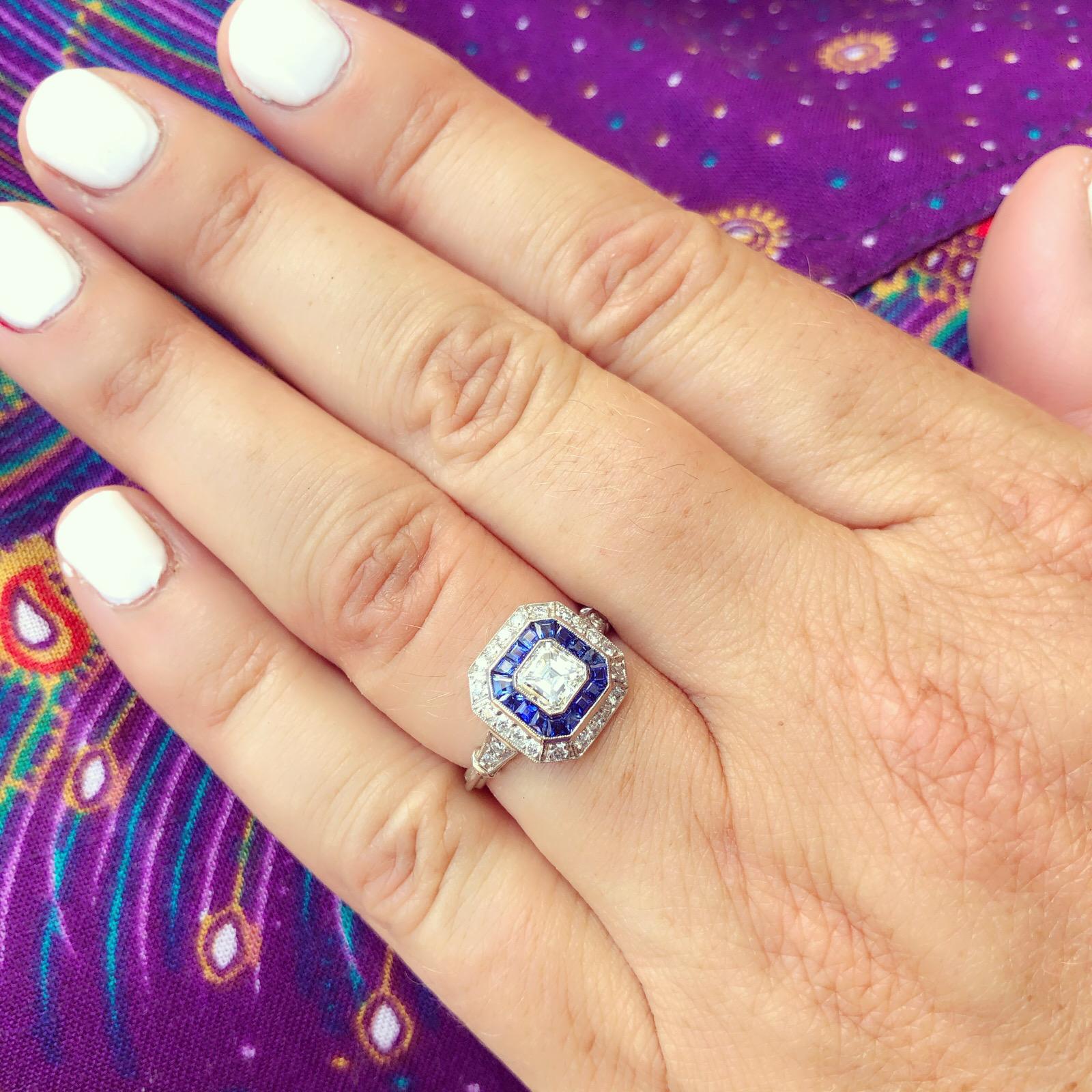 An Art Deco inspired 18k white gold ring for the ages! It centers around a gorgeous bezel-set Asscher-cut diamond, weighing an estimated 0.55 carat, G/VS, set within a frame of calibre-cut sapphires, and then a second frame of 24 round brilliant-cut